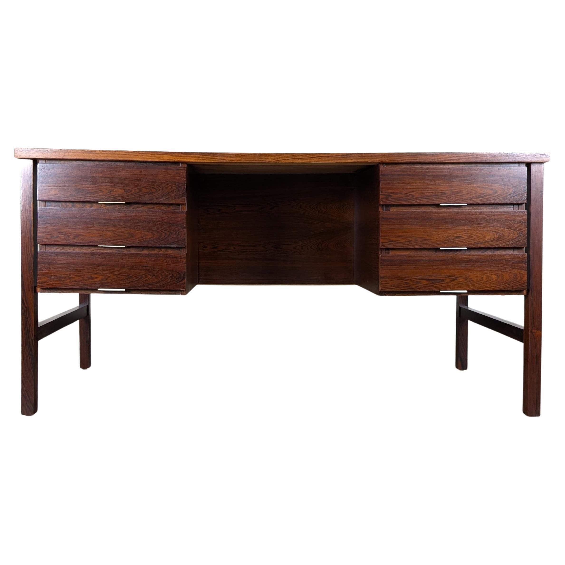 This stunning vintage Mid Century Modern rosewood desk, c1960s, is a timeless statement piece that effortlessly blends form and function. Crafted from richly grained rosewood and professionally refinished to showcase its natural beauty, this desk