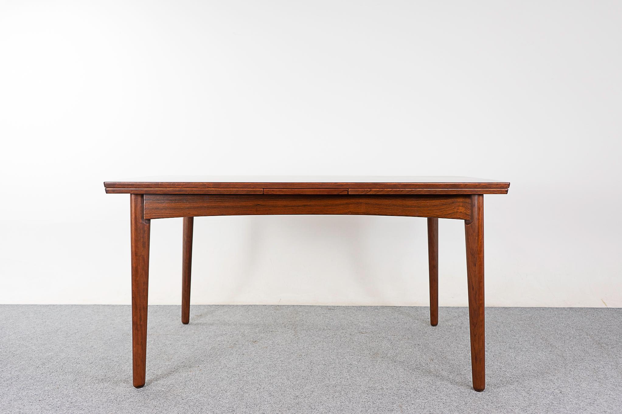 Rosewood Danish dining table, circa 1960's. Gentle curved edge and lovely grain patterns. Unique legs and self-storing leaves that slide out from each end to expand when needed.

Please inquire for remote and international shipping rates.