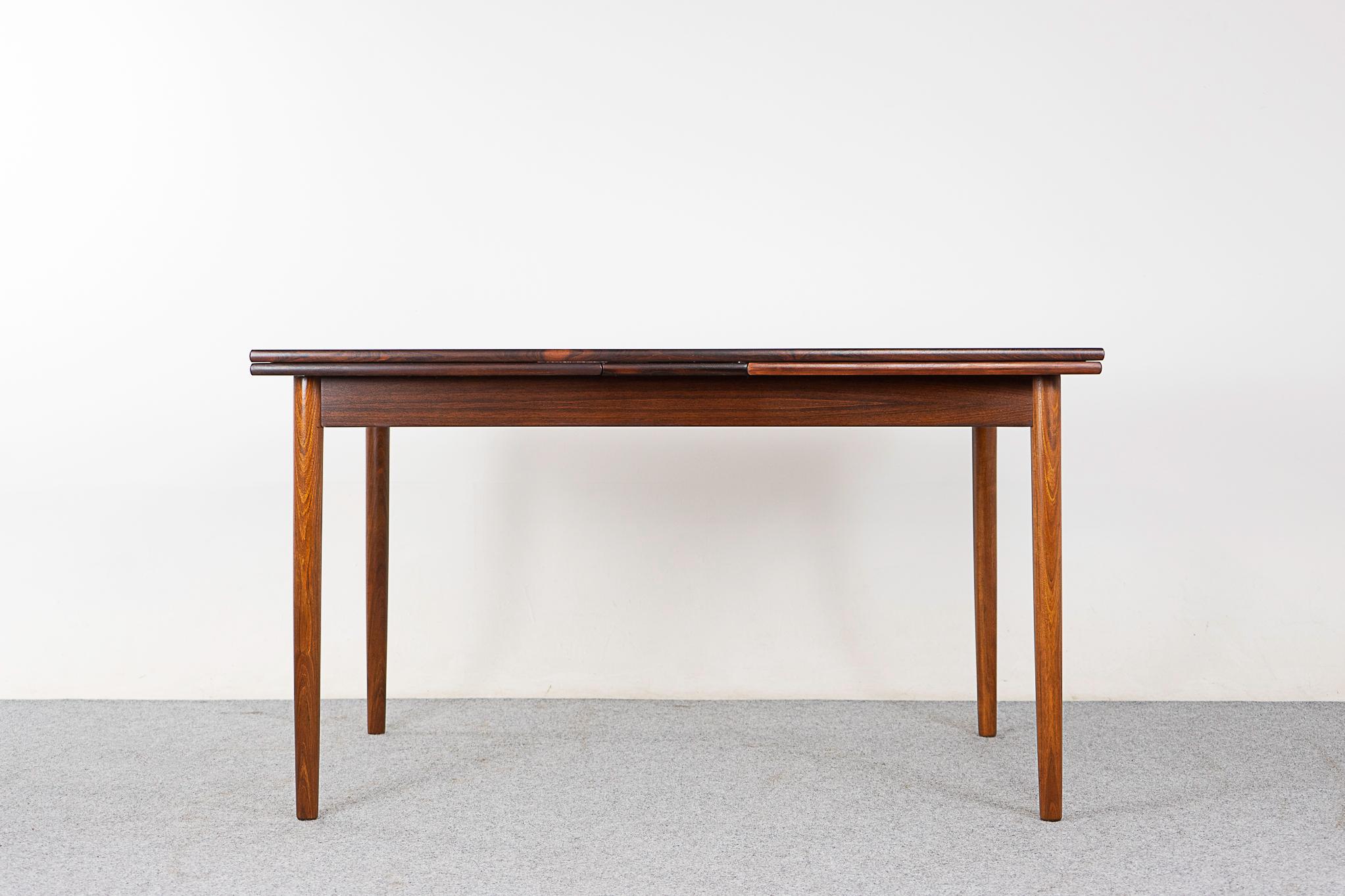 Rosewood mid-century dining table, circa 1960's. Self-storing leaves slide out from each end to expand the table surface by nearly two times. Excellent condition, great color, nice lines! 

Please inquire for remote and international shipping rates.