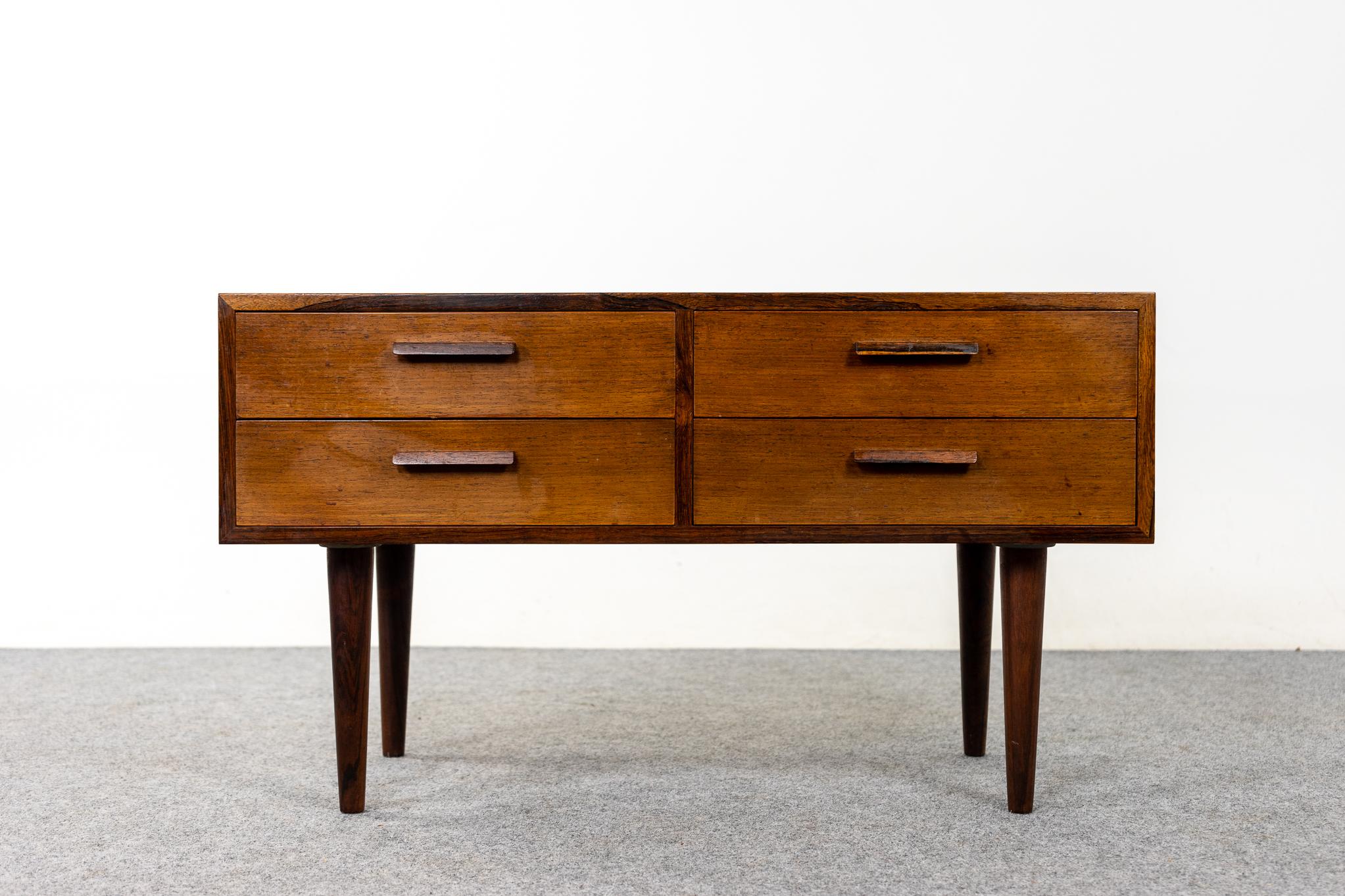 Rosewood Danish bedside table, circa 1960's. Beautifully veneered case rests on slender, tapered, removable legs. Four slim dovetailed drawers offer storage for small items.

Unrestored item, some marks consistent with age, small holes on