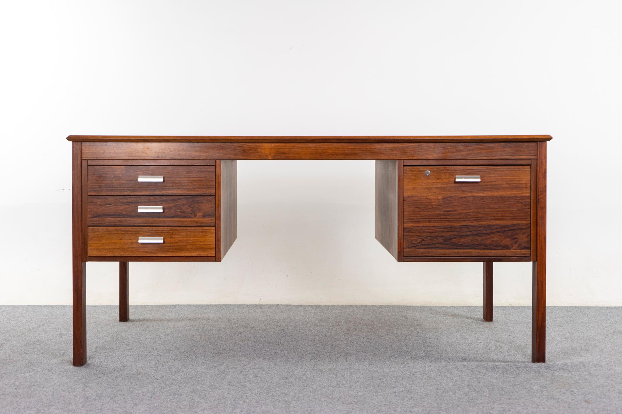 Bureau danois en bois de rose, vers les années 1970. Magnifique placage et garniture solide assortis. Poignées métalliques élégantes, tiroir profond pour dossiers suspendus et banque de tiroirs étroits. Fini des deux côtés, il est magnifique de tous