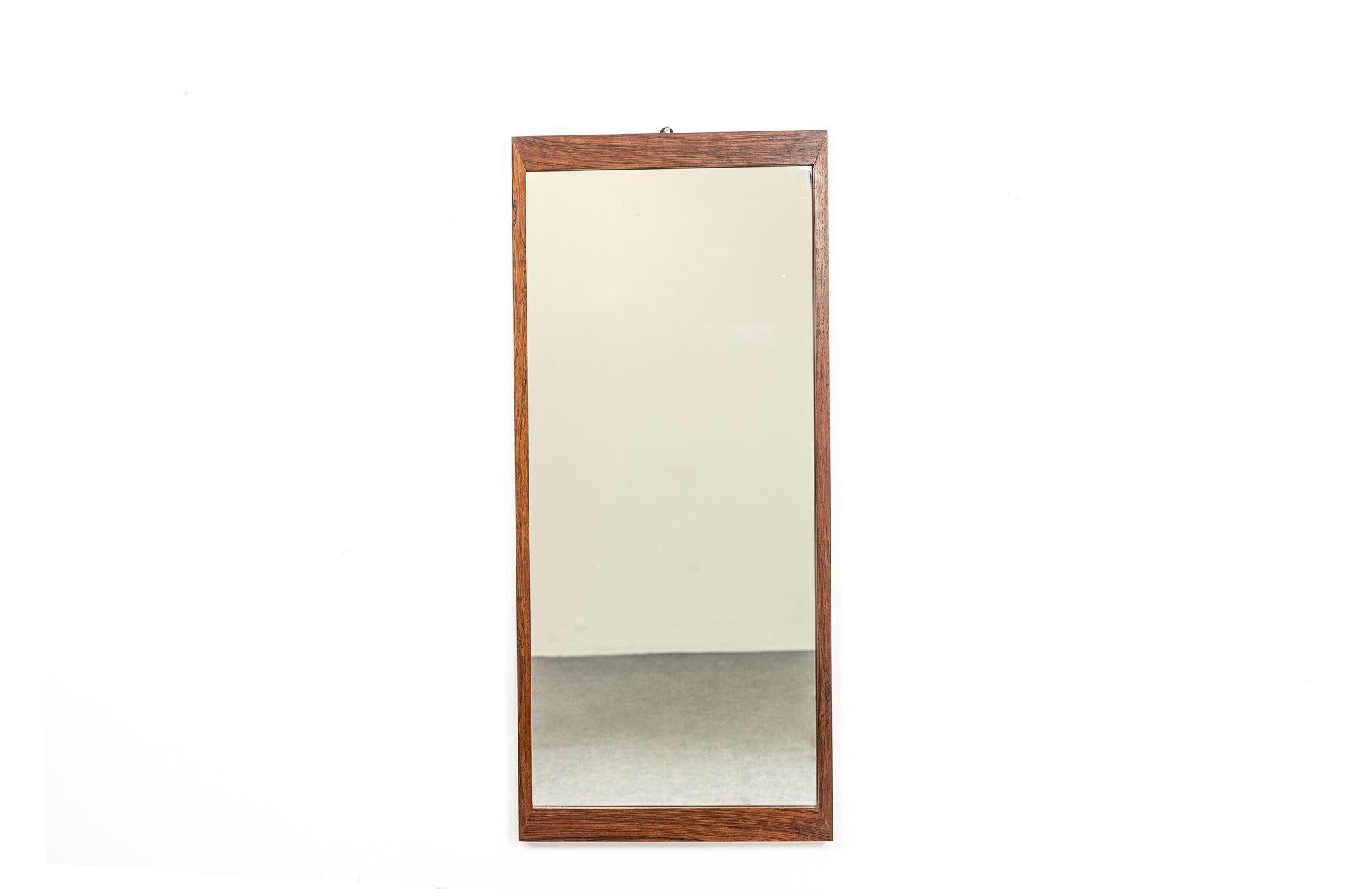 Rosewood Danish modern mirror, circa 1960's. Solid rosewood frame with stunning grain and mirror, original glass. Slim design is perfect for hanging near the door to check yourself before heading out.