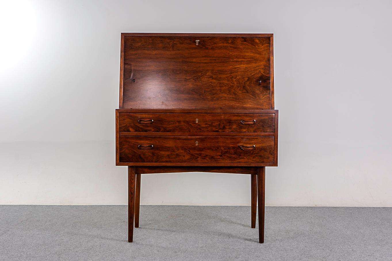 Rosewood Danish secretary desk, circa 1960's. Sleek angular profile and elegant tapering legs. Stunning bookmatched veneer case with contrasting beech wood fitted interior. Minor veneer bubble on drop down front.