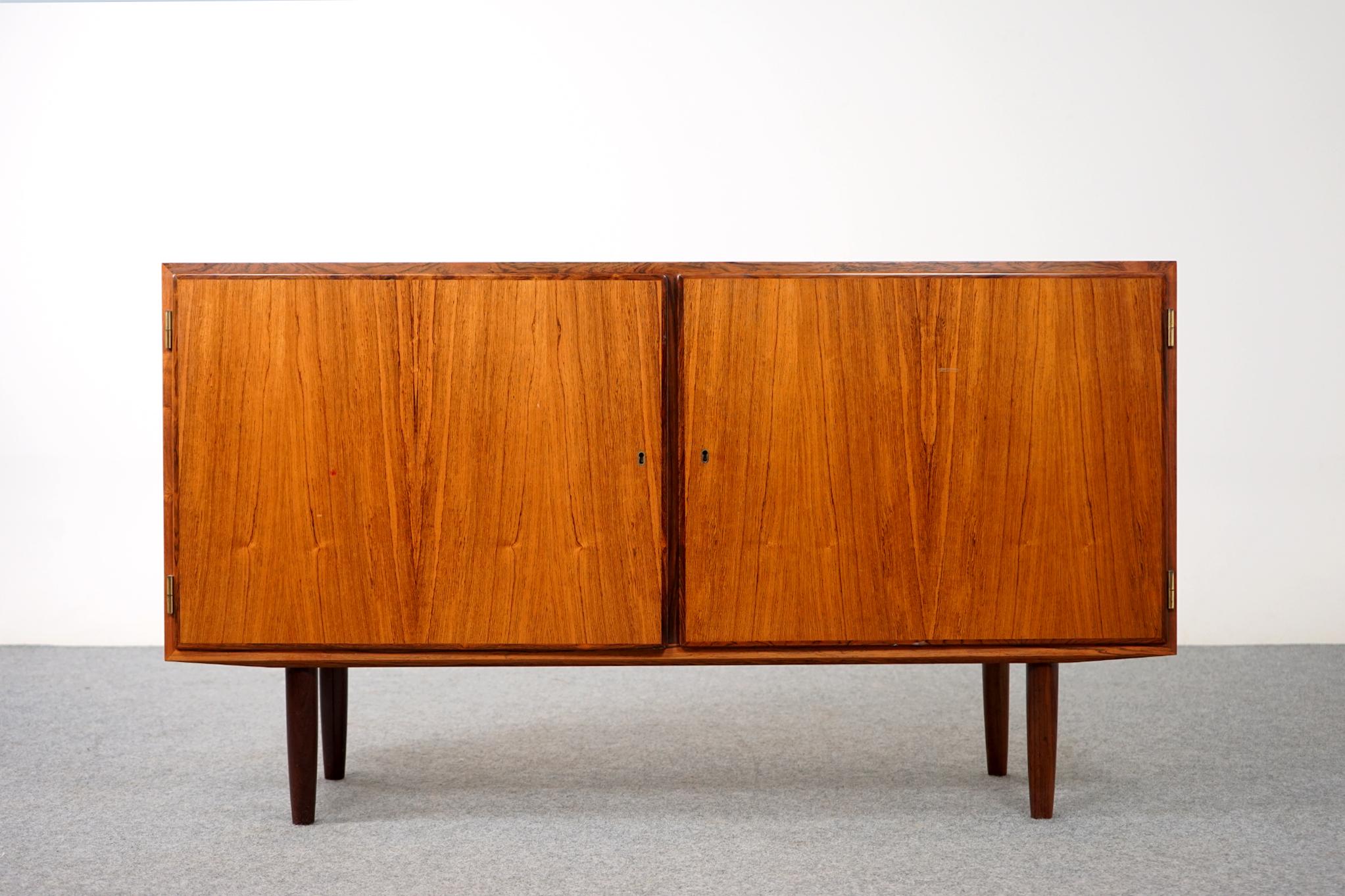 Rosewood double door sideboard by Hundevad, circa 1960's. Clean, simple lined design with exceptional book-matched veneer. Tapering cylindrical legs offer a light airy feel. Interior compartments have 2 adjustable shelves and 3 sleek adjustable