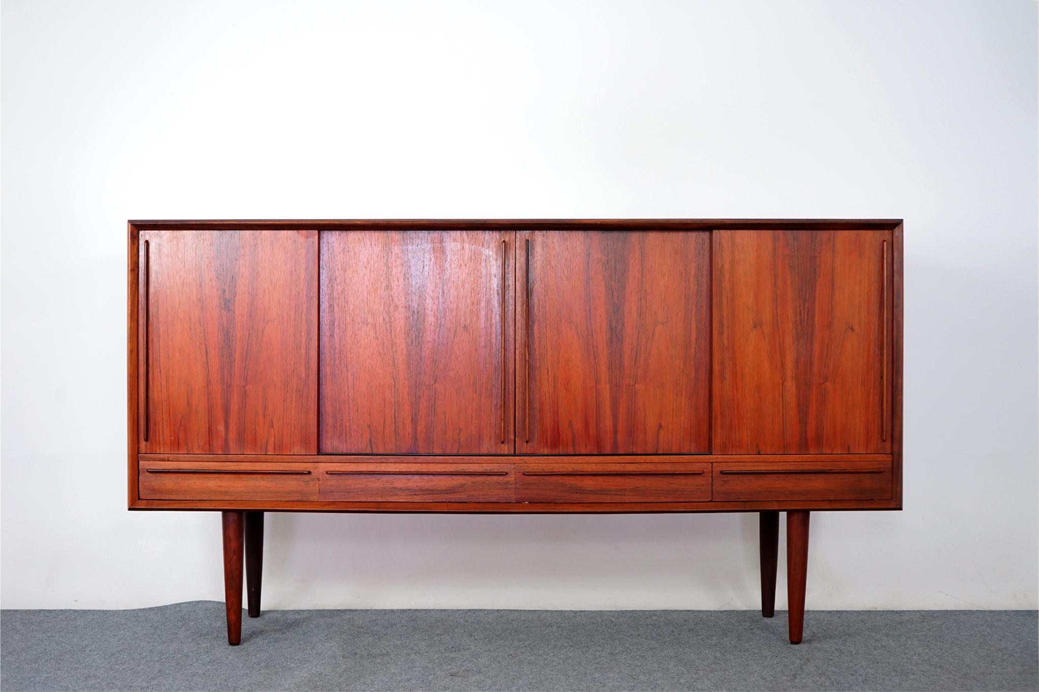 Rosewood Danish modern sideboard, circa 1960's. Gorgeous bow front with generous solid edge trim makes this piece a stand out! Clean, simple, graceful lines highlight the exceptional book-matched veneer doors. Interior compartments showcase 5