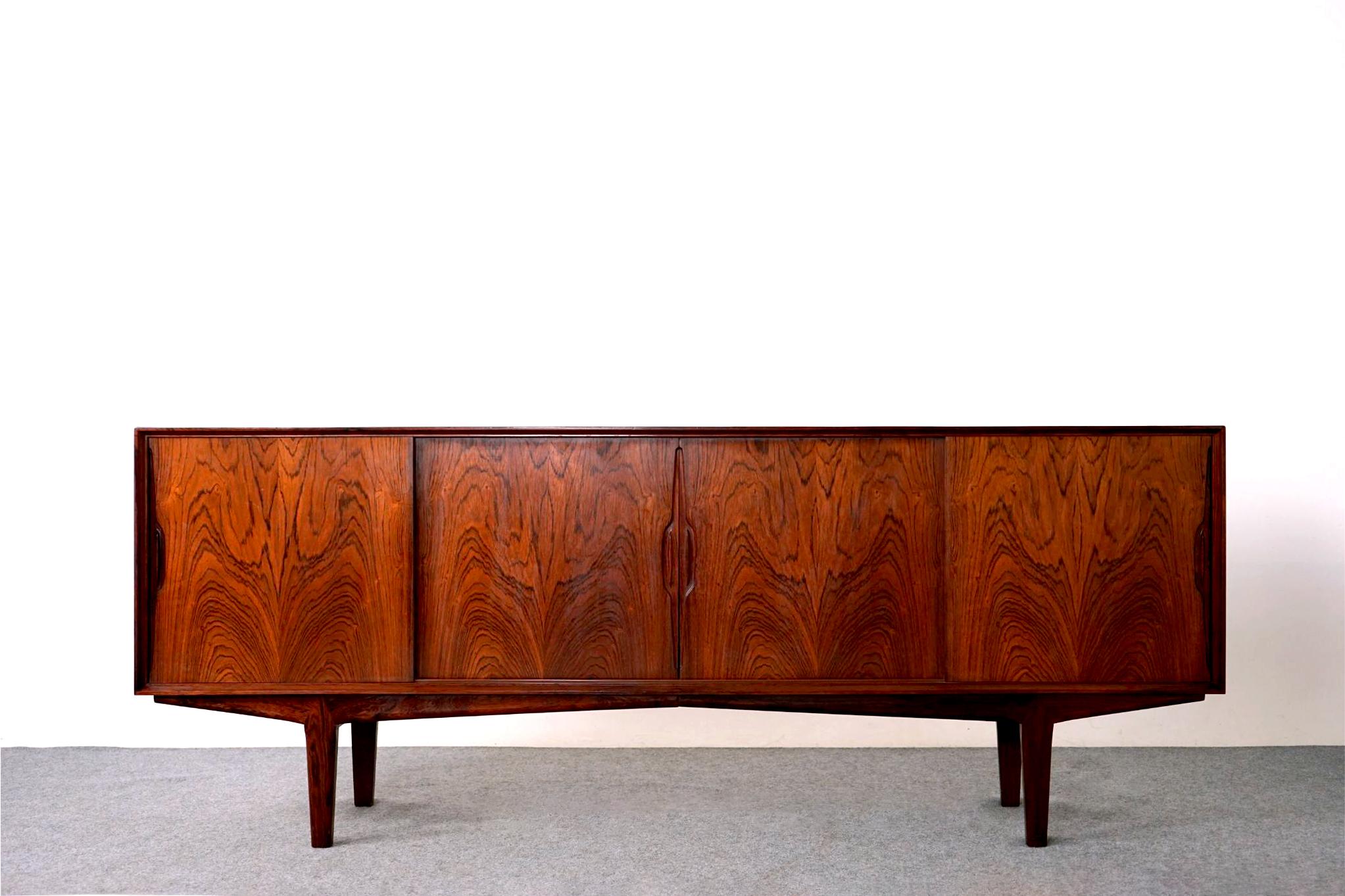 Rosewood Danish sideboard, circa 1960's. Clean, simple lined design with exceptional book-matched veneer, stunning! Low profile cabinet with adjustable shelving, removable legs and unique hand pulls. Interior compartments showcase shelving that can