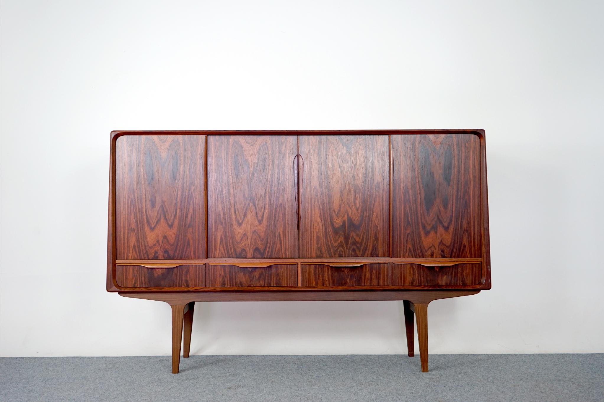 Rosewood mid century sideboard, circa 1960's. Clean, simple lined design highlights the exceptional book-matched veneer throughout. The elegant sleek, unique handles elevate this quality piece. A combination of sliding doors and exterior drawers,