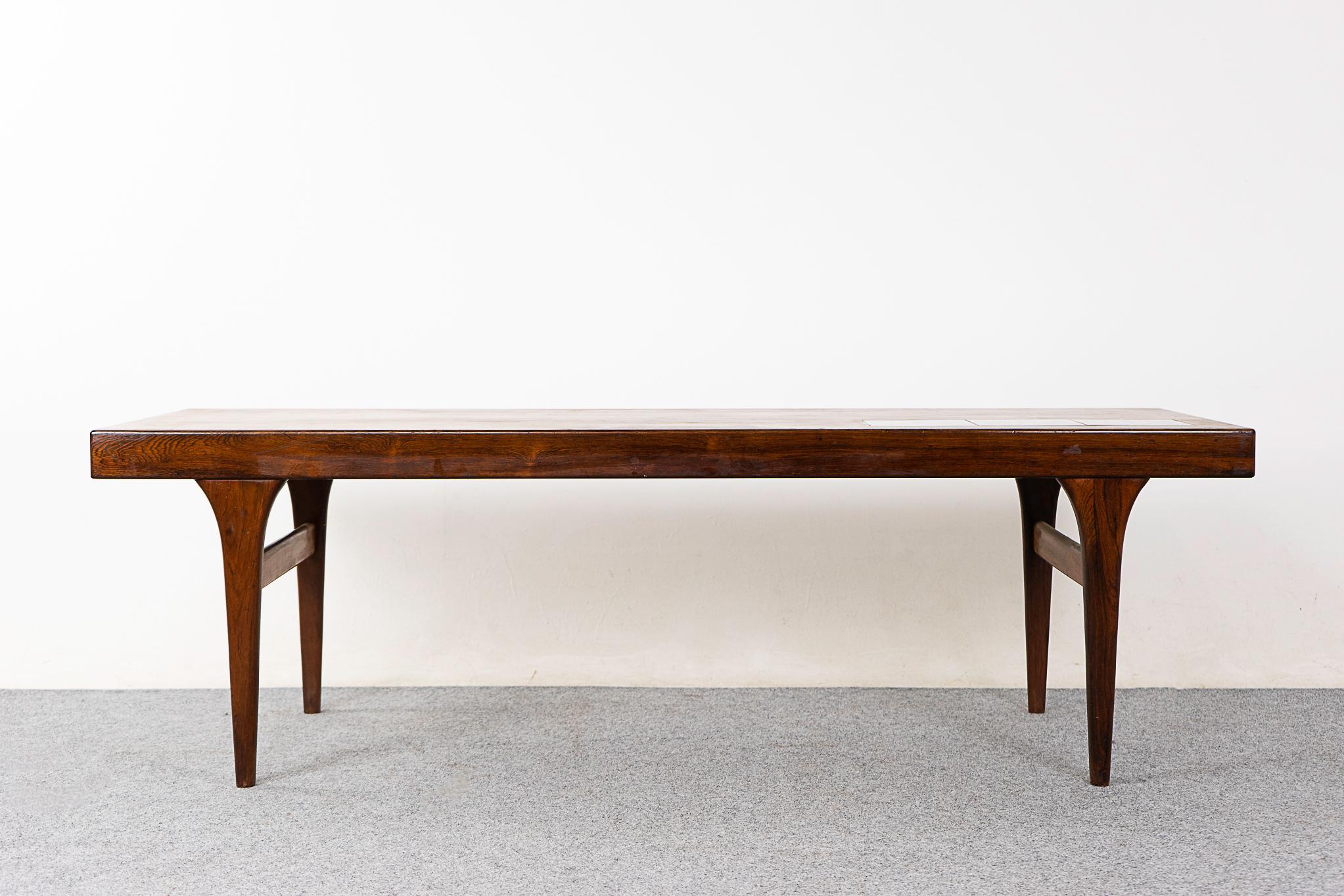 Rosewood mid-century coffee table designed by Johannes Andersen for CFC Silkeborg, circa 1960's. Beautiful book matched veneer on the top and a solid wood curved edge along its length. The ceramic tiles are an ideal spot for placing your beverage!
