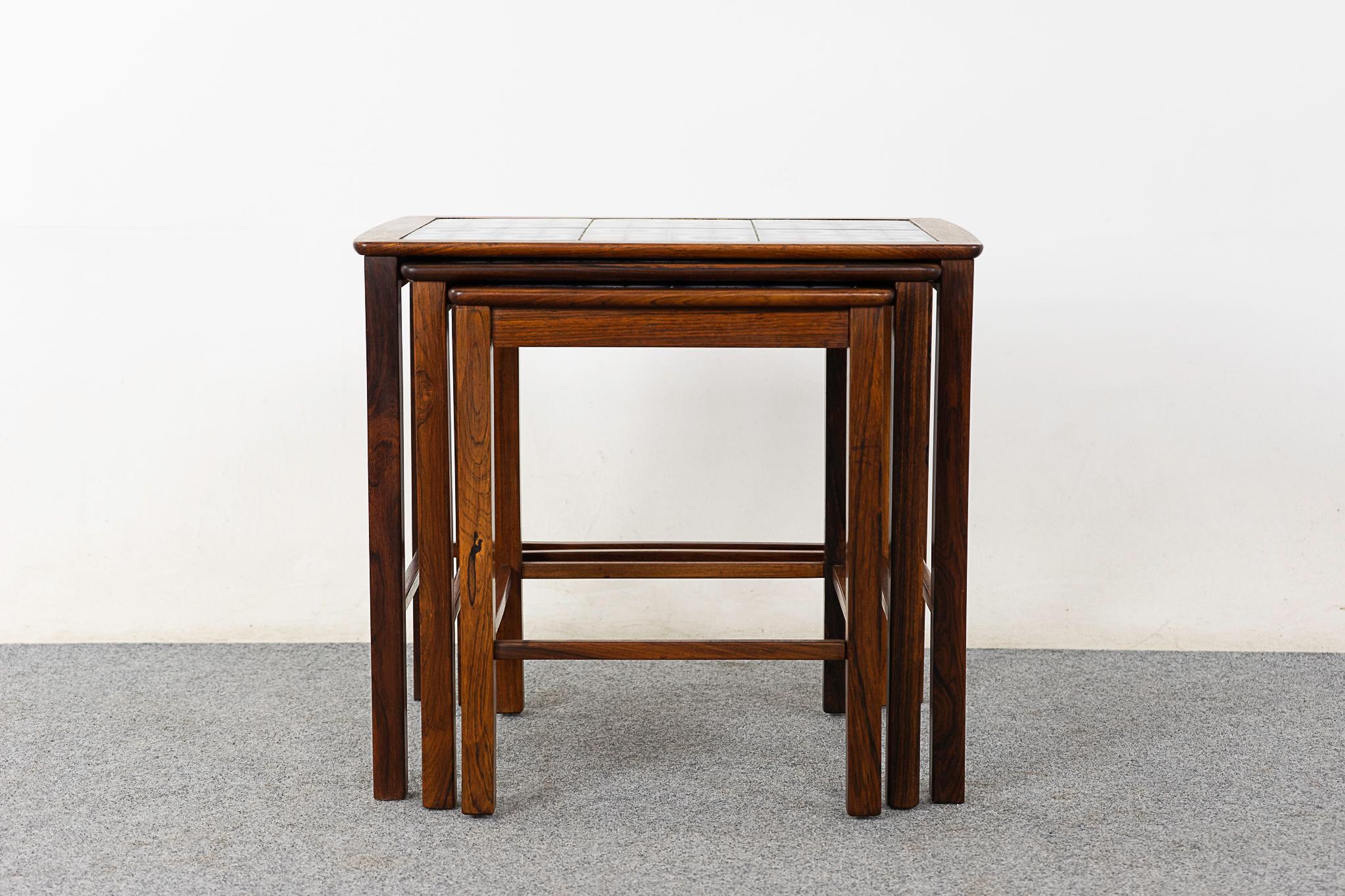 Rosewood & tile mid-century nesting tables, circa 1960's. Charming floral motif tiled tops, framed in stunning rosewood. Space saving design, footprint of one table with the functionality of three! 

Unrestored item, some marks consistent with age.