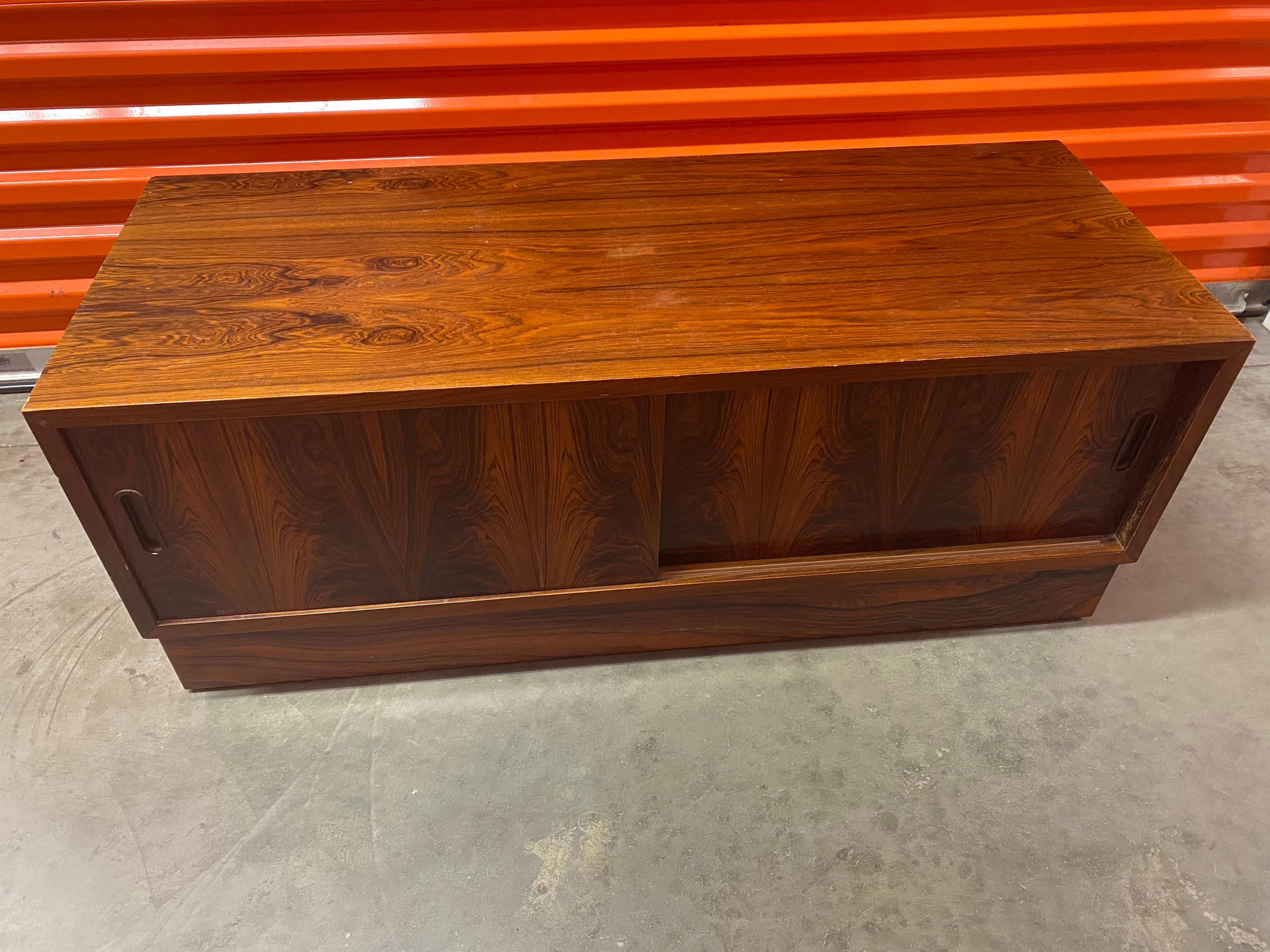 Danish Mid-Century Modern rosewood TV cabinet. Small Rosewood cabinet with sliding doors. The left side has one slide-out shelf with open space below; the right has one open cubby. Great for small storage. Suggested use as a TV cabinet. Made in