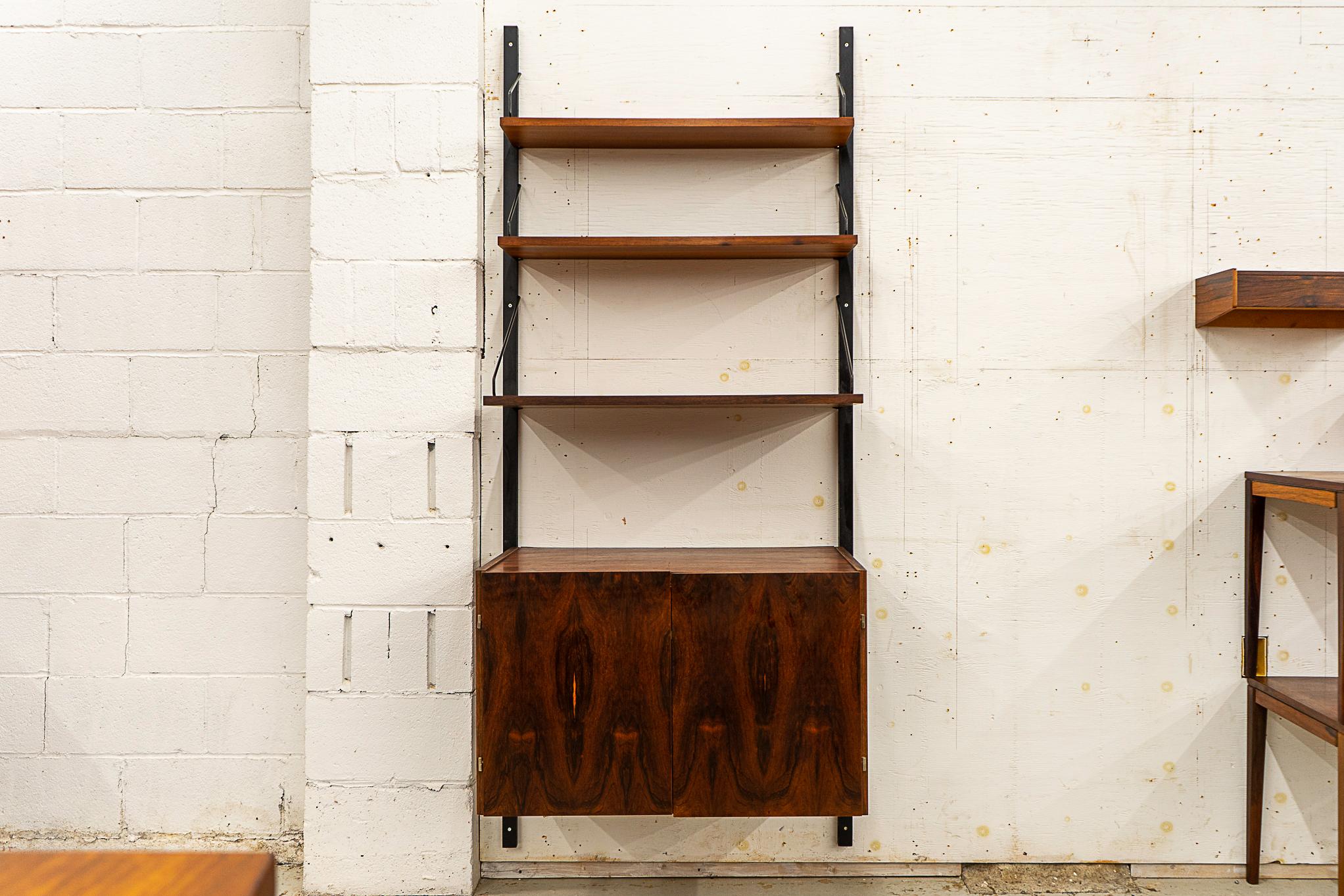 Rosewood Danish wall system, circa 1960's. Double door cabinet with beautiful bookmatched veneer, interior shelf and open cubby. Three height adjustable shelves with graduating depths of 7