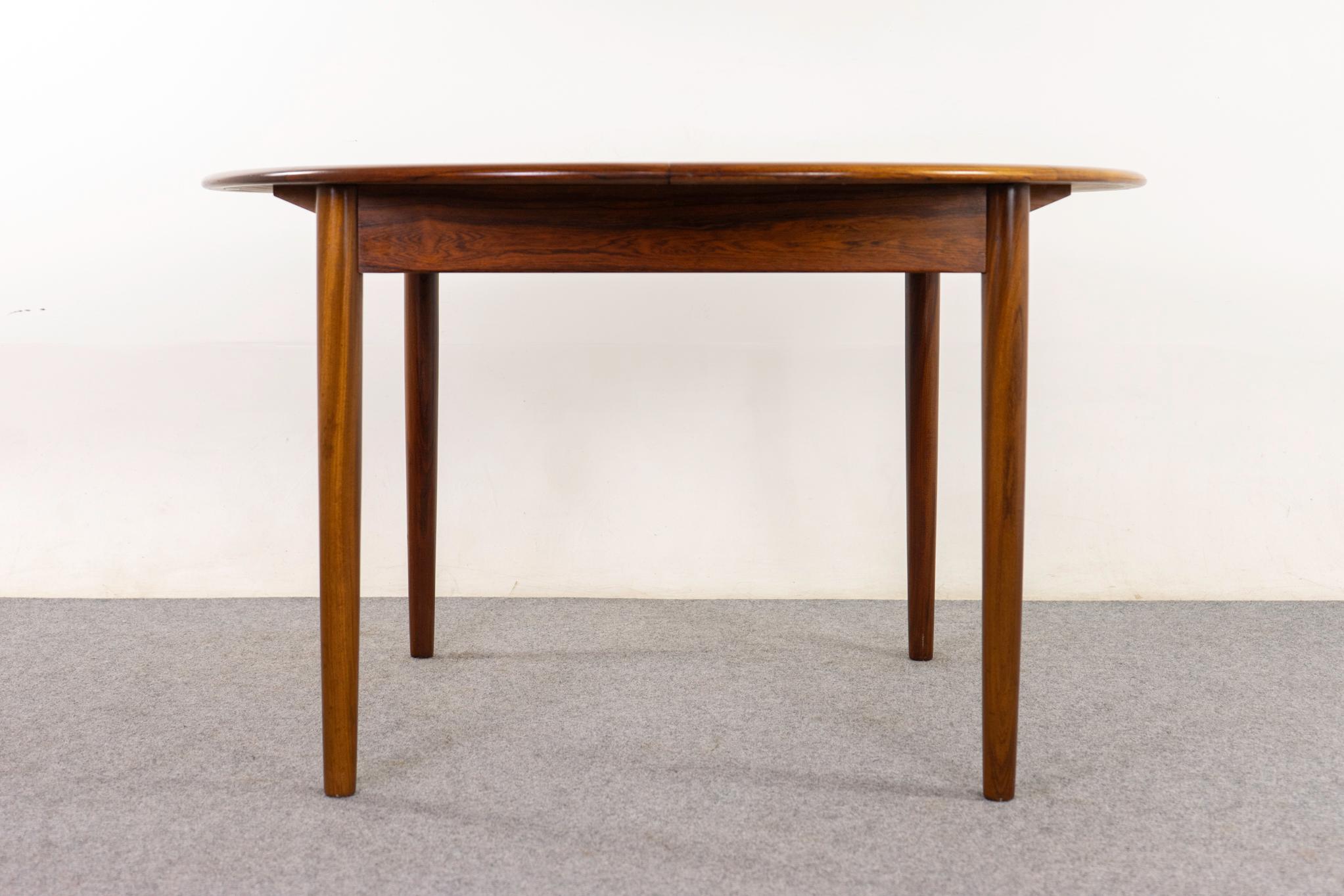 Rosewood dining table, circa 1960's. Top is framed in solid wood, center features highly figured veneer with book-matched grain. Top slides open to access self storing butterfly/jackknife leaf.

Unrestored item with option to purchase in restored
