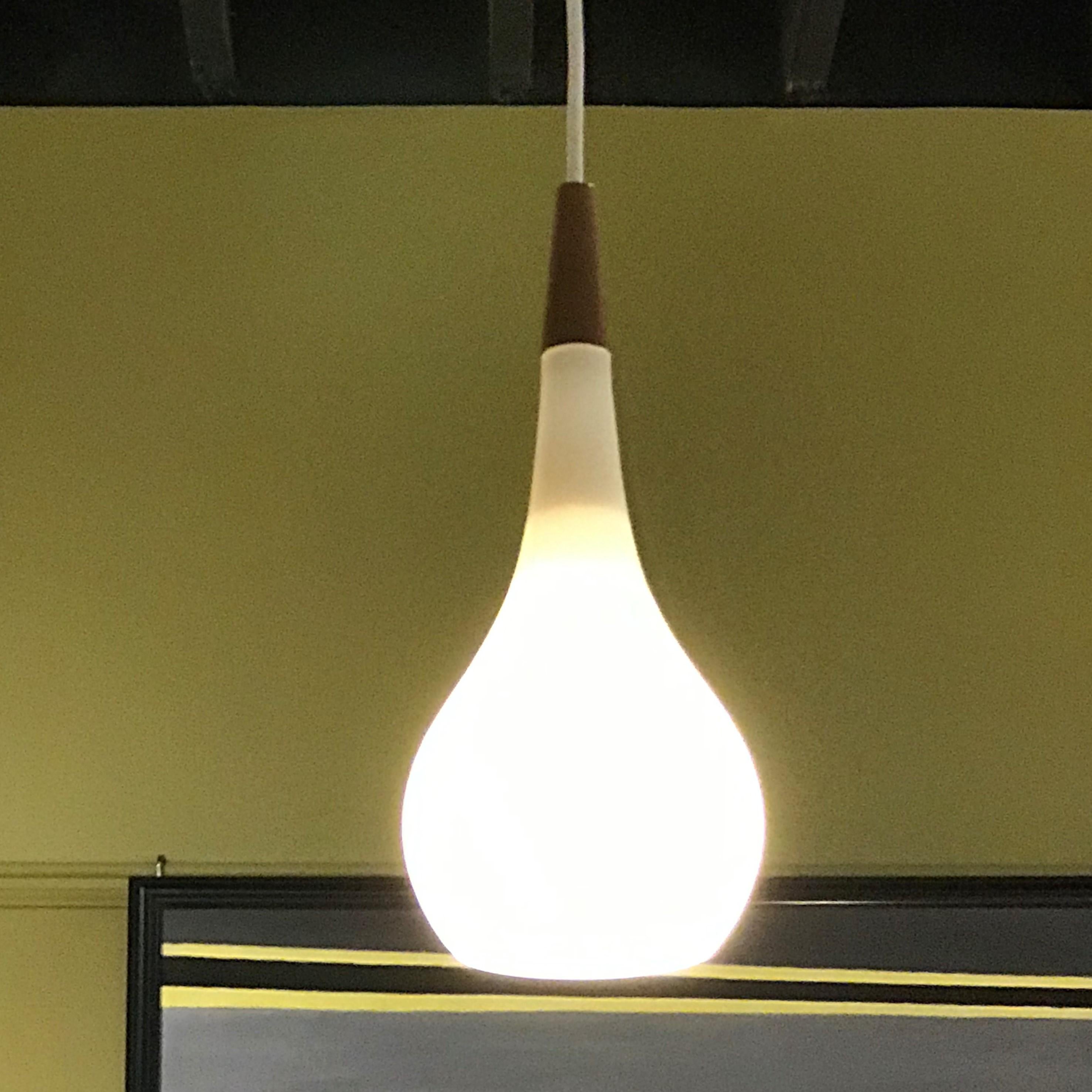 1950s Danish satin glass and teak teardrop pendant. A beautiful teardrop shaped blown satin glass globe with a teak top. Rewired with new cordage and original UL approved socket taking a standard base bulb and new ceiling canopy. 75 watts max, we