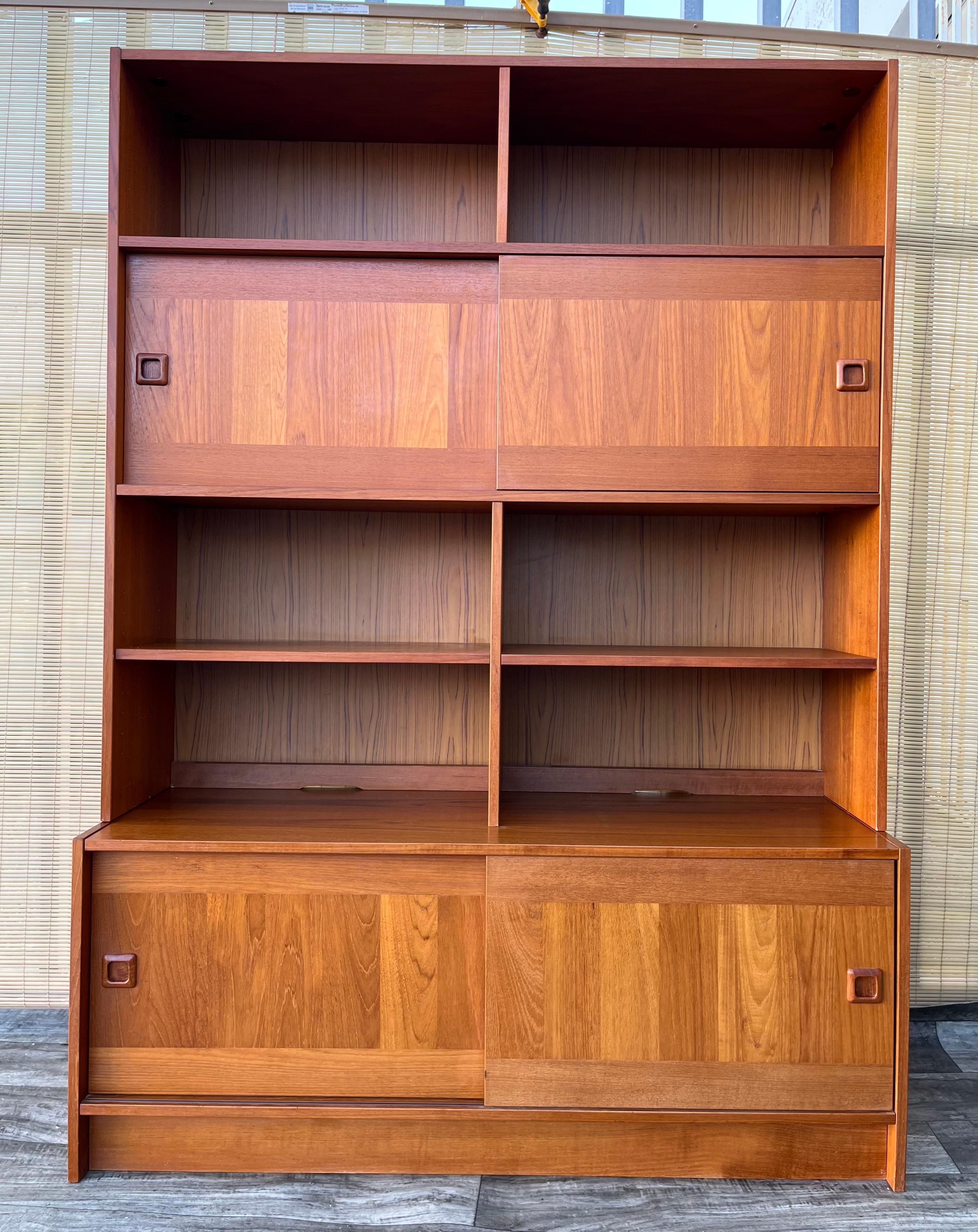 Vintage Danish Mid Century Modern Shelving Cabinet by Domino Mobler Denmark. Circa 1970s
Features a sleek Scandinavian Mid Century Modern design, a beautiful teak wood grain, two compartments with sliding doors and plenty of additional storage with