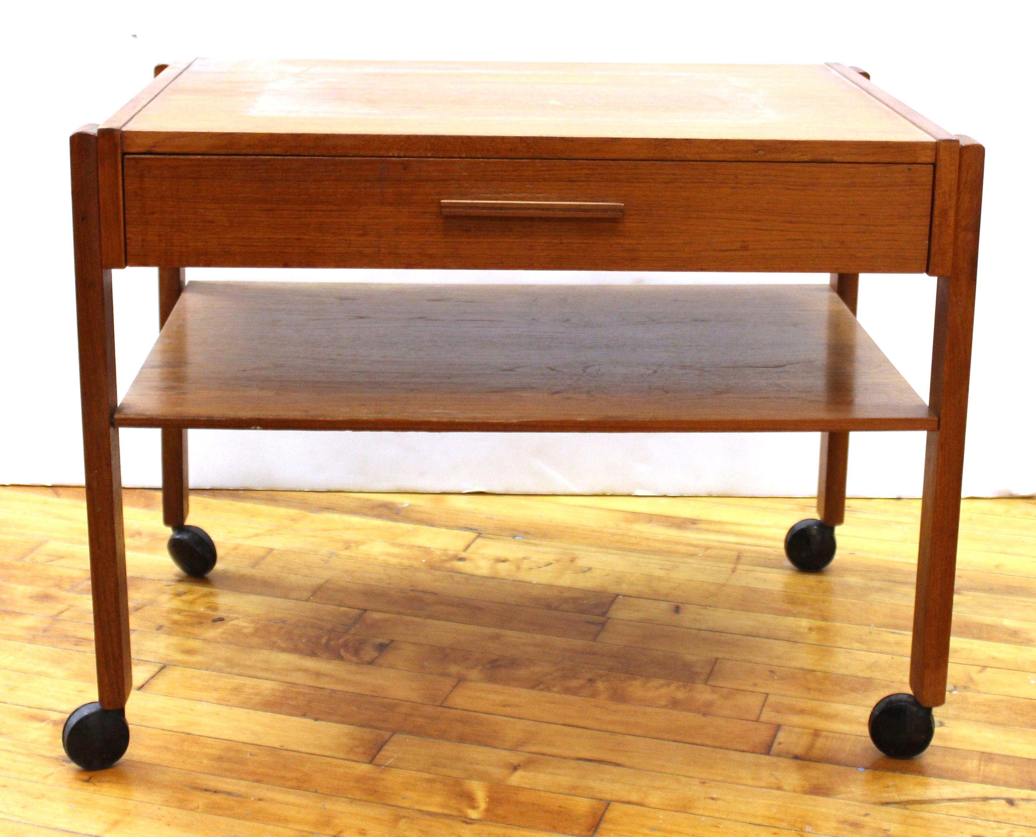 Danish Mid-Century Modern side table in teak wood, on casters, with one flat drawer with white interior. The piece was made during the 1950s and is in great vintage condition with age-appropriate wear and use.