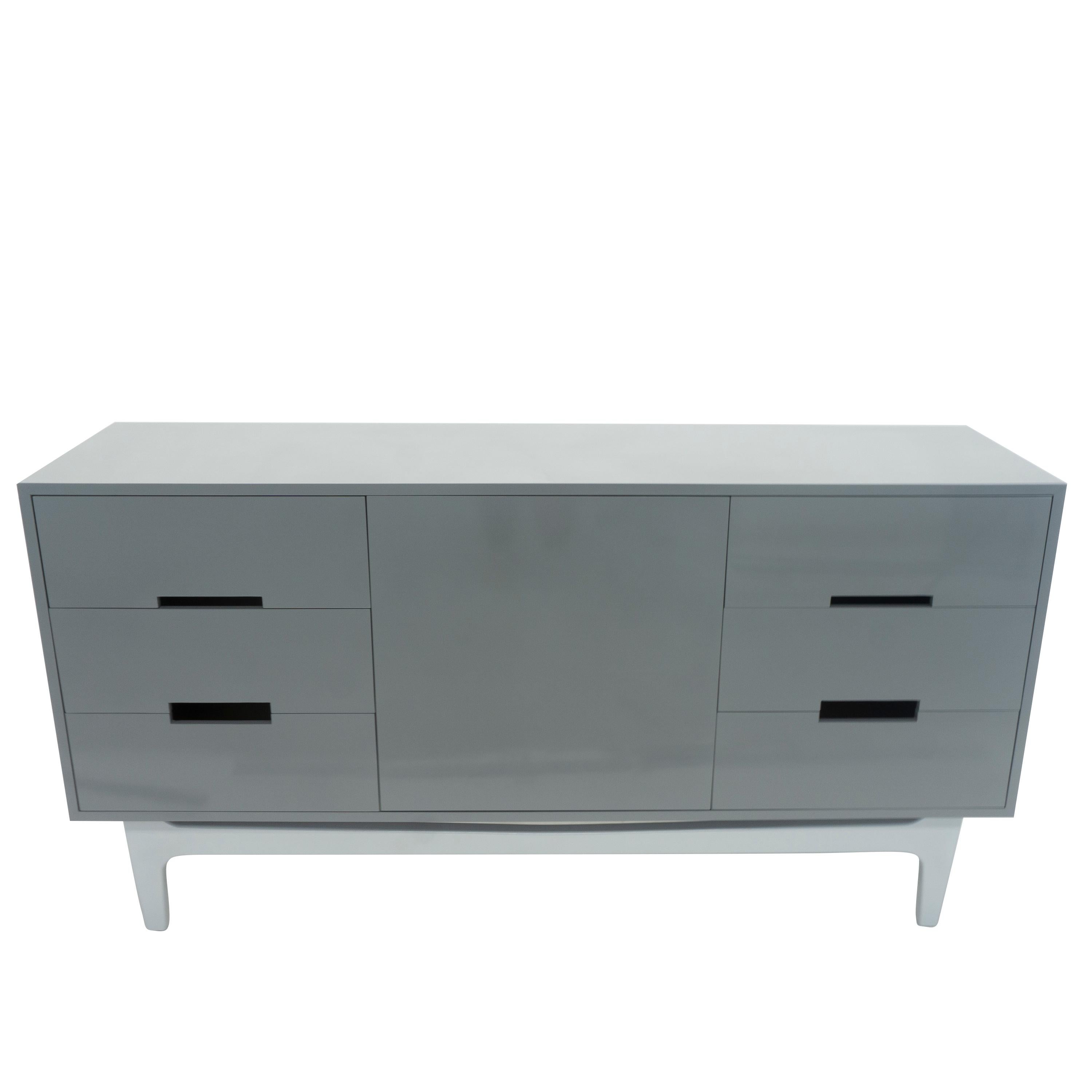 A Danish Mid-Century Modern inspired design featuring six drawers and a center push magnet door that opens into more storage space. Each drawer has carved recessed handles with slow closing rails that open to reveal the natural wooden interior. The