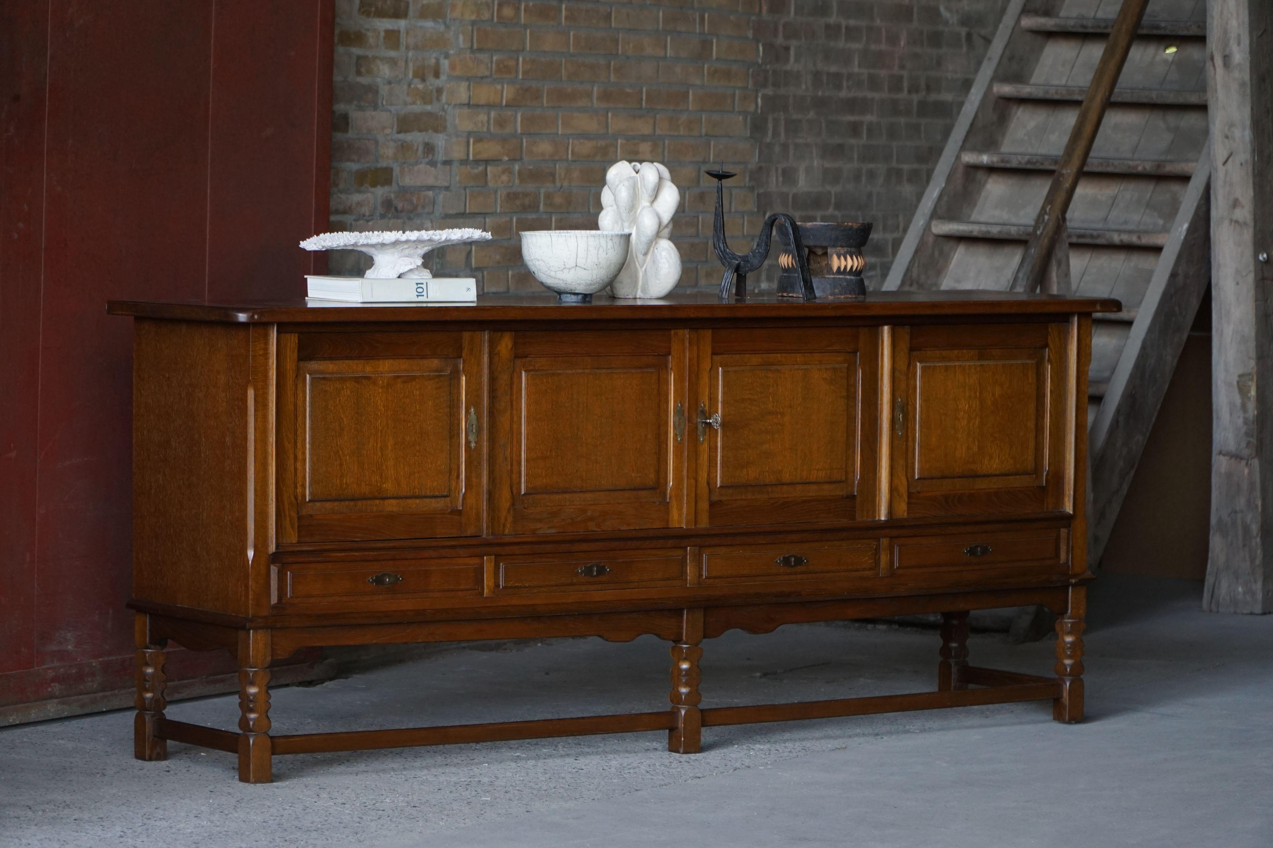 Elegante aparador bajo de roble teñido oscuro, con un frente bellamente tallado y amplio espacio de almacenamiento. Fabricada al estilo de Henning Kjærnulf para Nyrup Møbelfabrik en la década de 1960, esta pieza muestra las cualidades audaces y