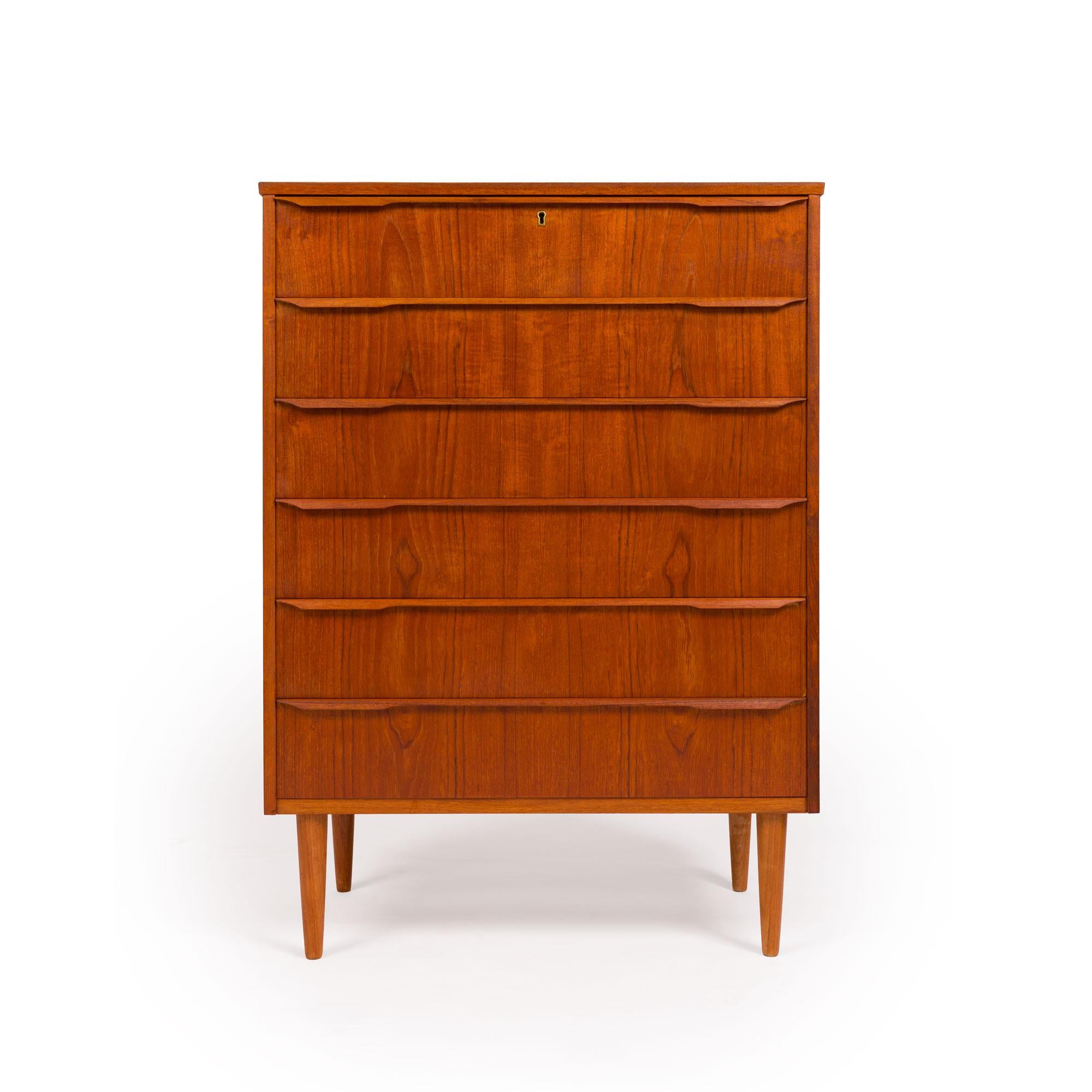 This beautiful Danish Modern Mid-Century Six-Drawer Teak Tallboy was made in Denmark in the 1960s. With handsome wood-grain detail, this chest has six drawers with hand-carved teak drawer pulls. Recently reconditioned and in excellent condition,
