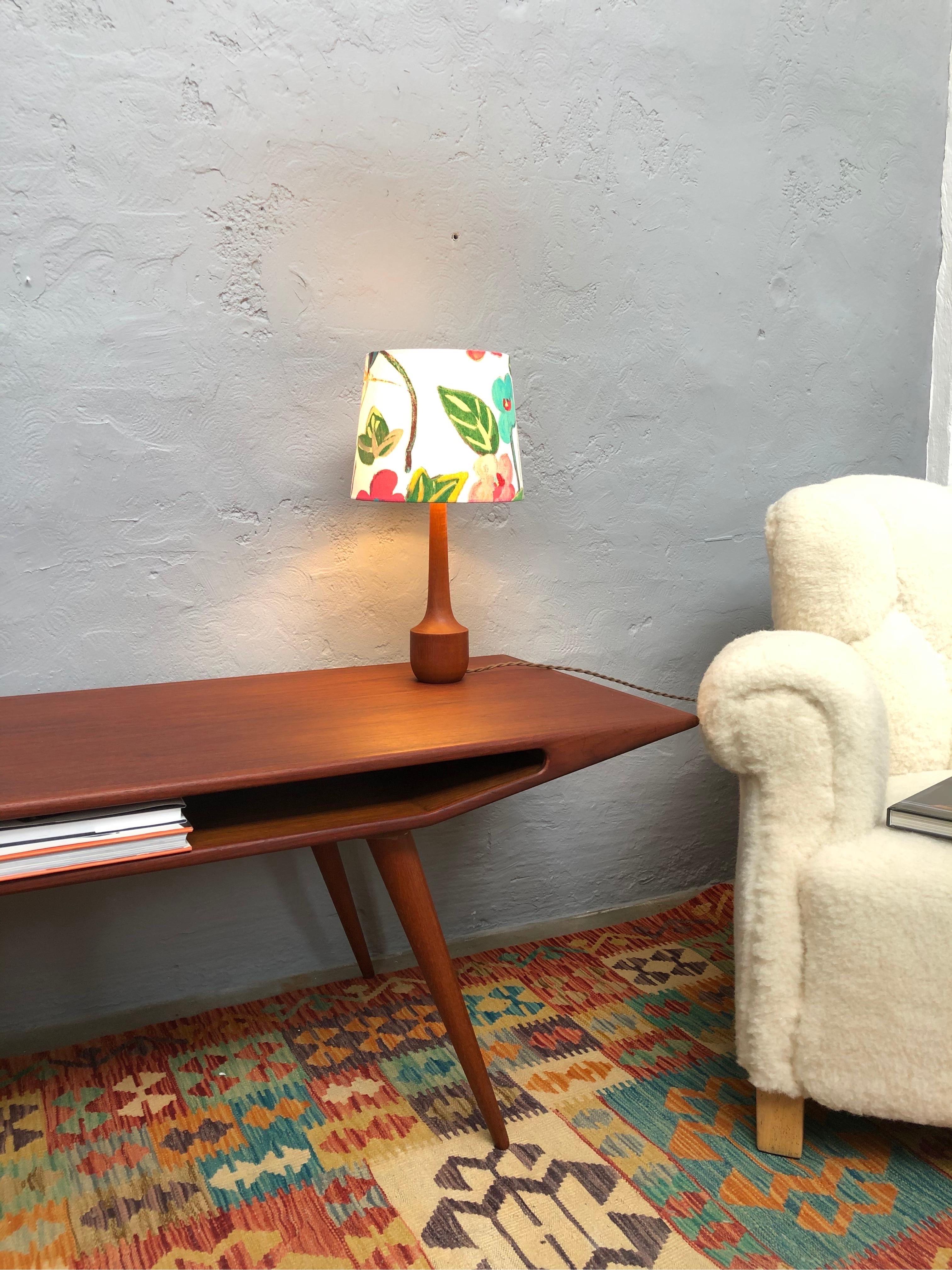 Vintage Danish Mid-Century Modern turned solid teak table lamp with a very elegant period design. 
Rewired and topped with a limited edition lampshade from ArtbyMaj in the manner of Josef Frank.
This beautiful floral design on a white cotton