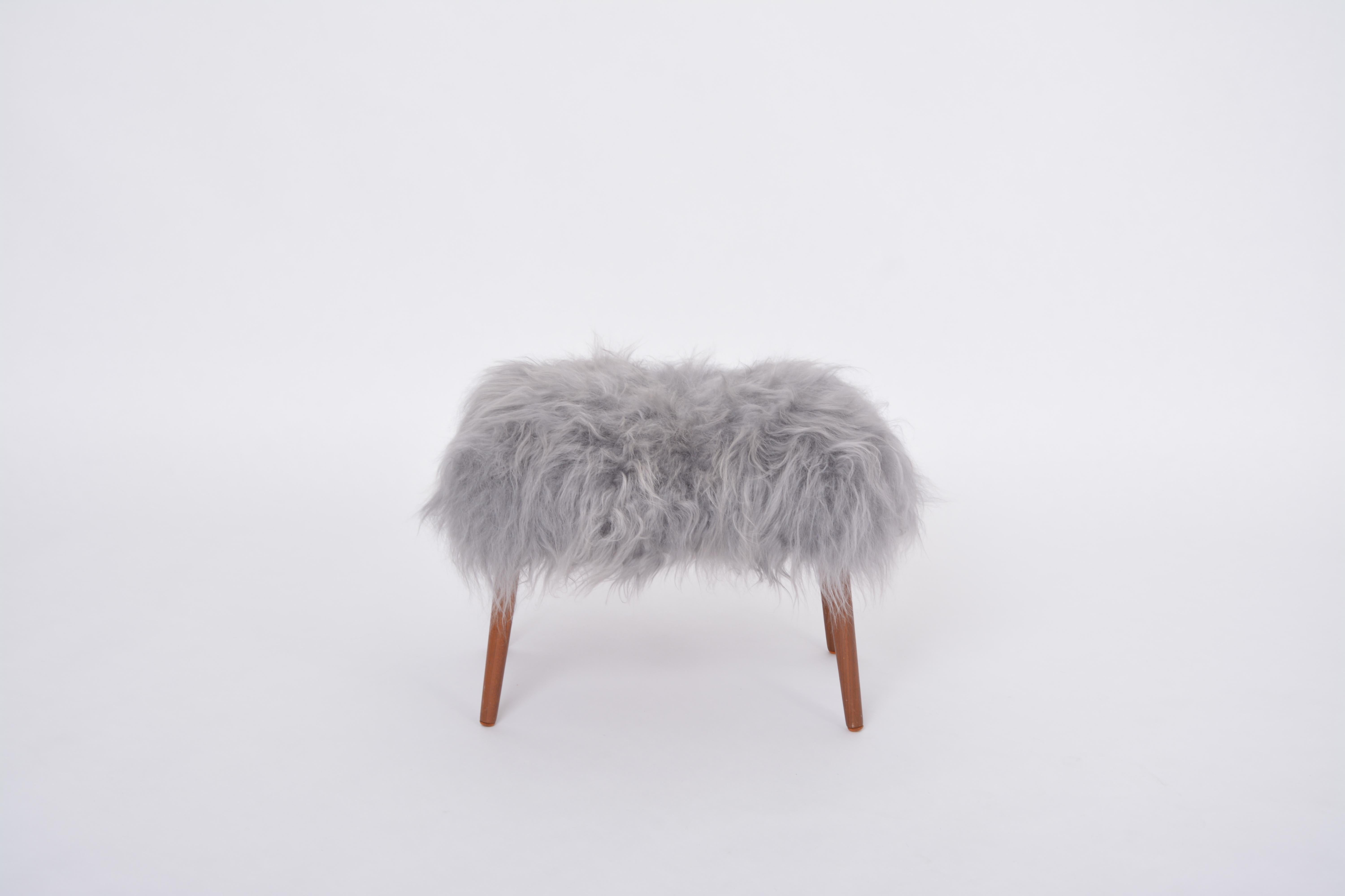 Danish Mid-century Modern stool reupholstered in grey sheep skin
This ottoman/pouf/ stool was designed and manufactured in the 1950s in Denmark. It is made of  wood and has been reupholstered with a long haired grey sheep skin.  By choosing this