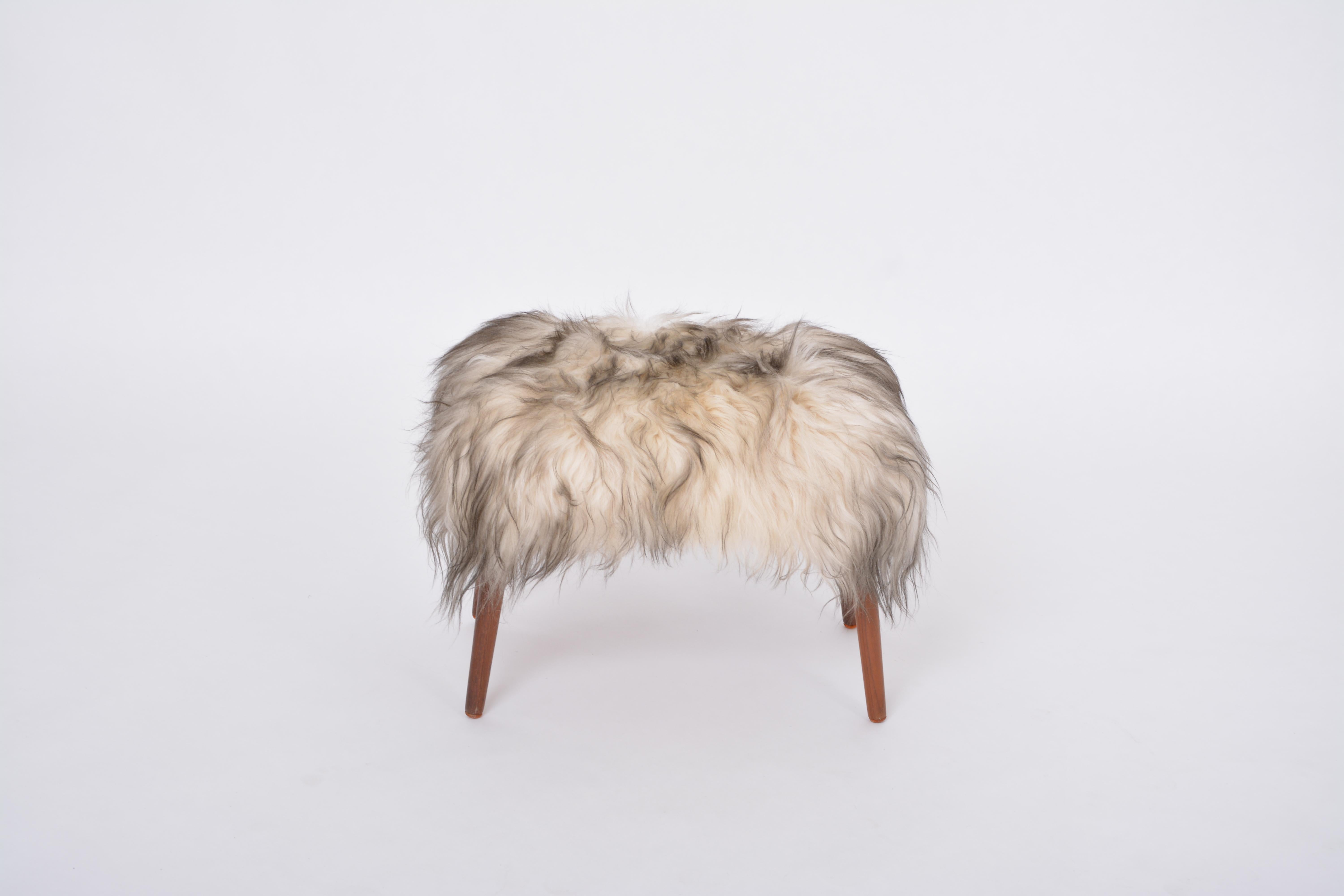 Danish Mid-century Modern stool reupholstered in white and black sheep skin
This ottoman/pouf/ stool was designed and manufactured in the 1950s in Denmark. It is made of  wood and has been reupholstered with a long haired white and black sheep skin.