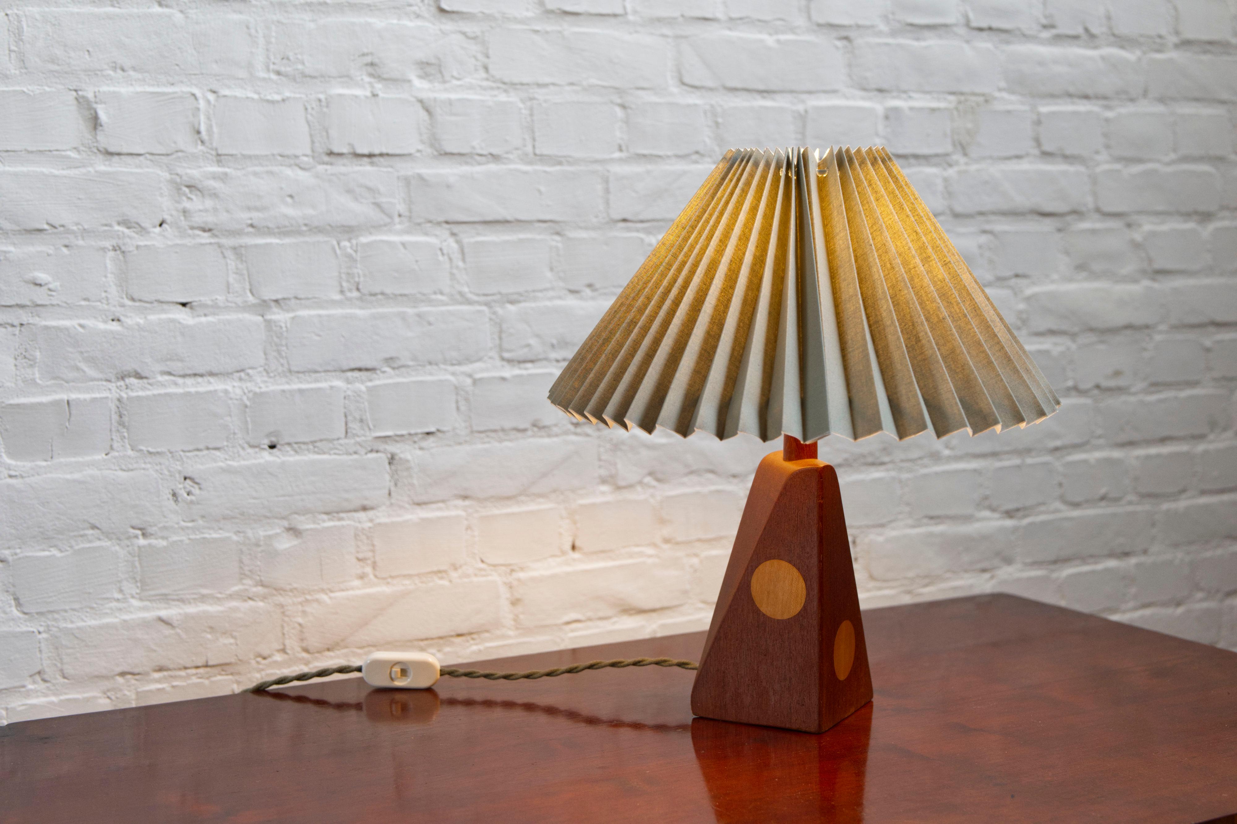Lampada da tavolo danese in teak della metà del secolo scorso con dettagli in beeche intarsiato. 
paralume plissettato in lino verde - anni '60

Bellissimo esempio di artigianato danese di metà secolo, questa lampada da tavolo degli anni '60