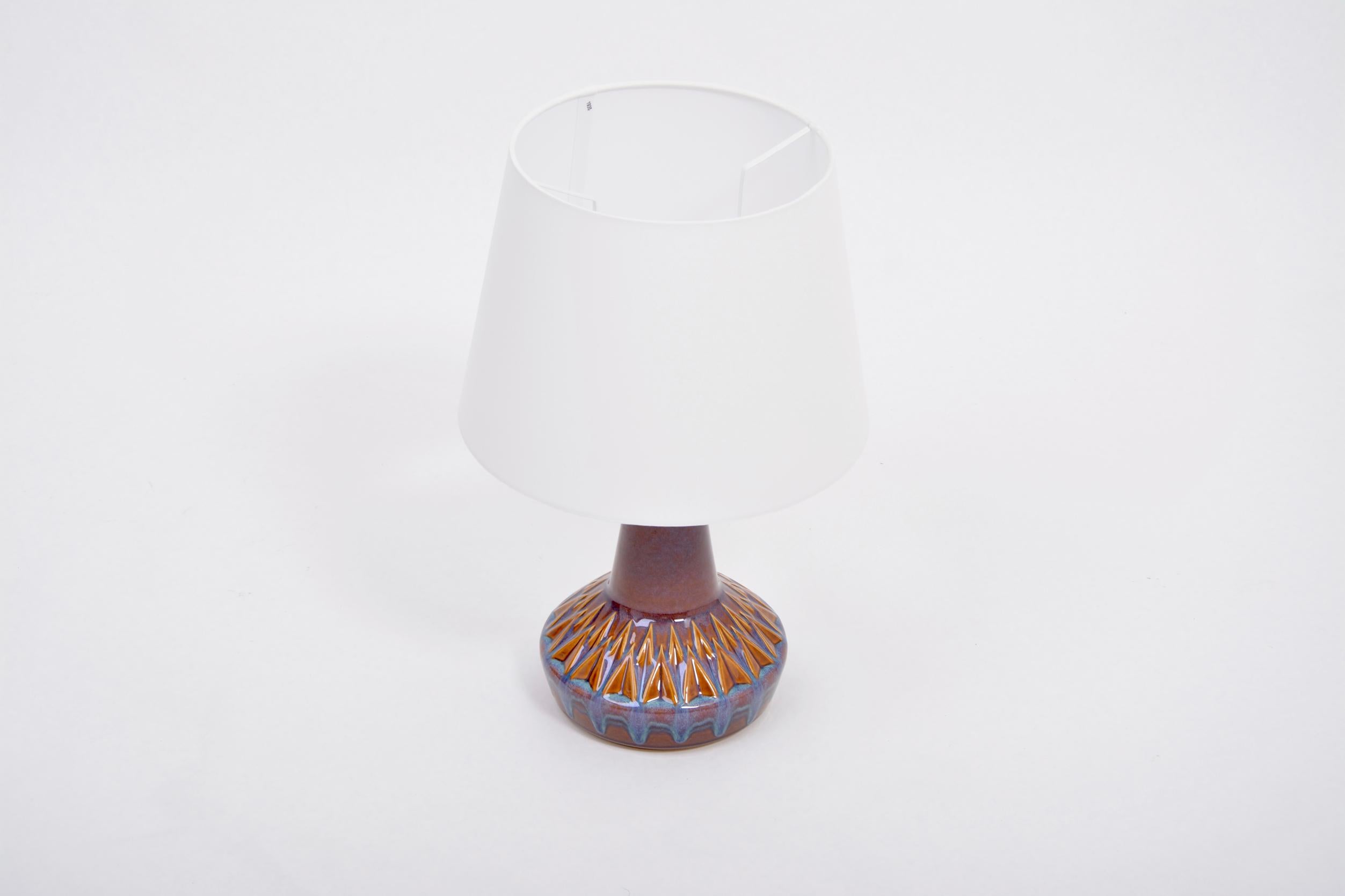 Danish Mid-Century Modern table lamp model 1058 by Soholm

Stoneware table lamp with geometric pattern to its base produced in Denmark by Soholm. Beautiful ceramic glazing in tones of brown and blue. The lamp has been rewired for European use and