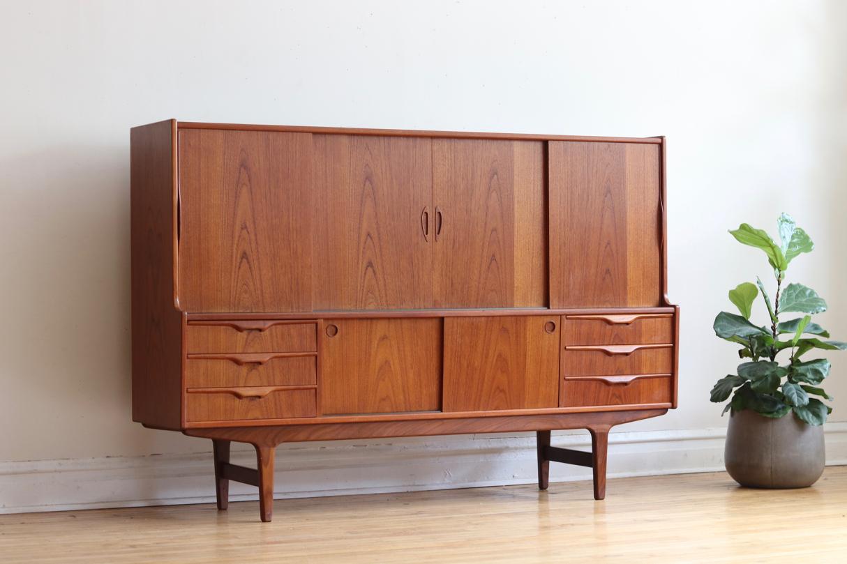 Mid-Century Modern Danish tall teak credenza.
Made by A. Petersen for Højslev, Denmark 1960s.
Just imported from Copenhagen!
Beautiful book-matched teak woodgrain.
Features an etched mirror bar in right compartment.
Sculptural handles and