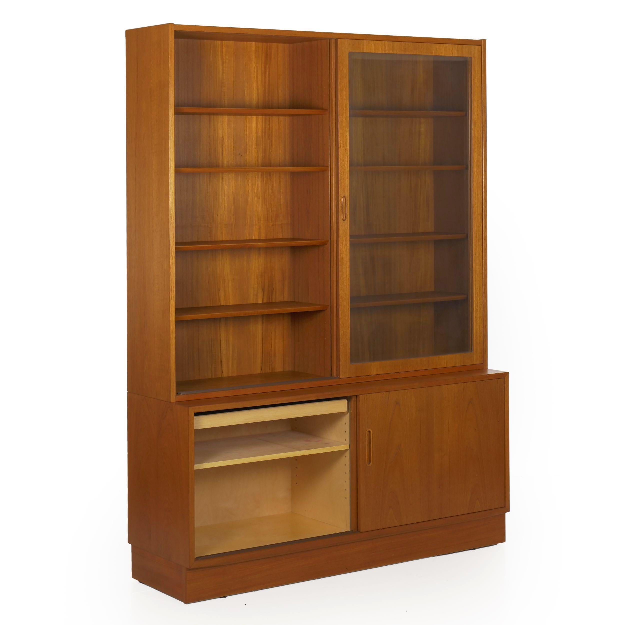 A striking two-part bookcase cabinet by Poul Hundevad, this distinctive Danish modern vintage bookcase cabinet is angular and austere with its pleasing teak veneers and orderly grain profile. The two upper doors slide easily on track to give access