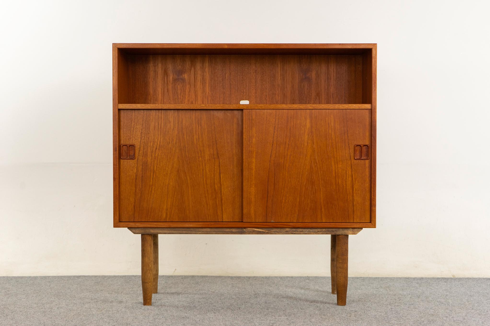 Teak Danish bookcase/cabinet, circa 1960s. Teak veneered case with smooth operating sliders, removable shelf, and tapered legs. 

Unrestored item with option to purchase in restored condition for an additional $200 USD. Restoration includes: