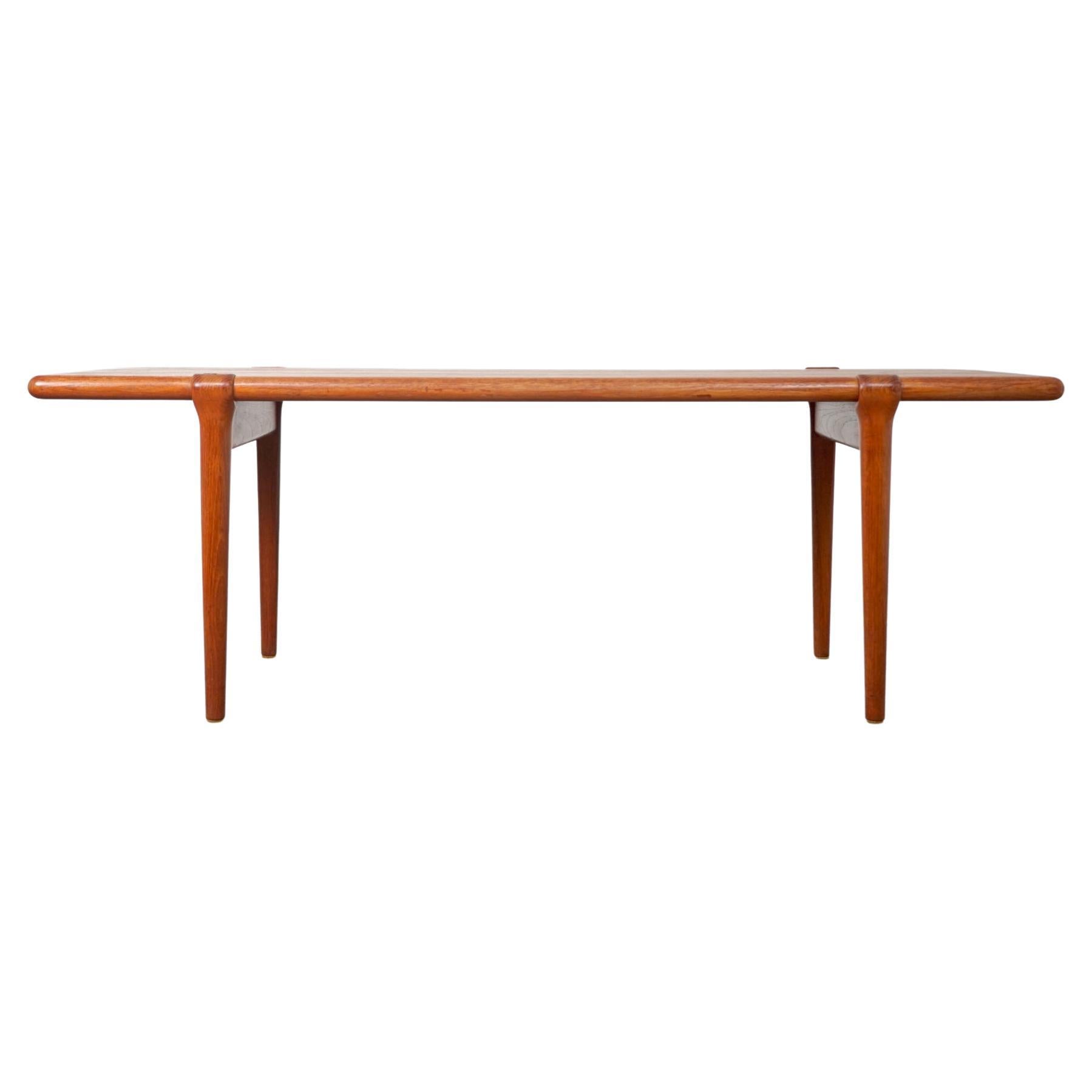 Teak tall Danish coffee table designed by Niels Moller, circa 1960's. Beautiful book matched veneer on top surface, solid wood curved edge along its length. Sculpted legs that curve over the top edge make this a unique piece. Stunning.

Finish has