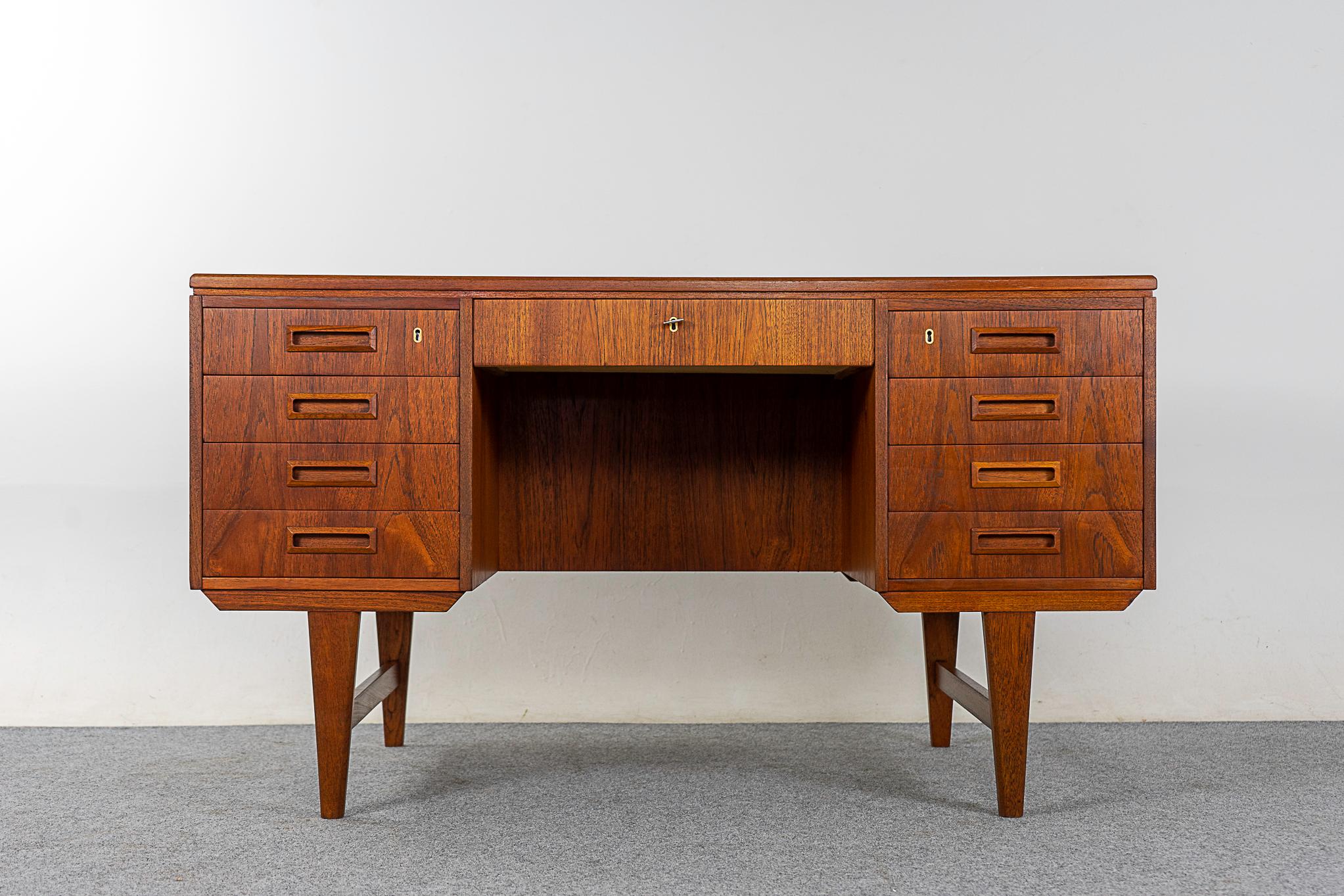 Teak mid-century desk, circa 1960's. Finished on both sides, this desk can be placed in the center of a room and look fantastic from every vantage point! Two banks of drawers with dovetail construction and bookmatched veneer. Stunning condition,