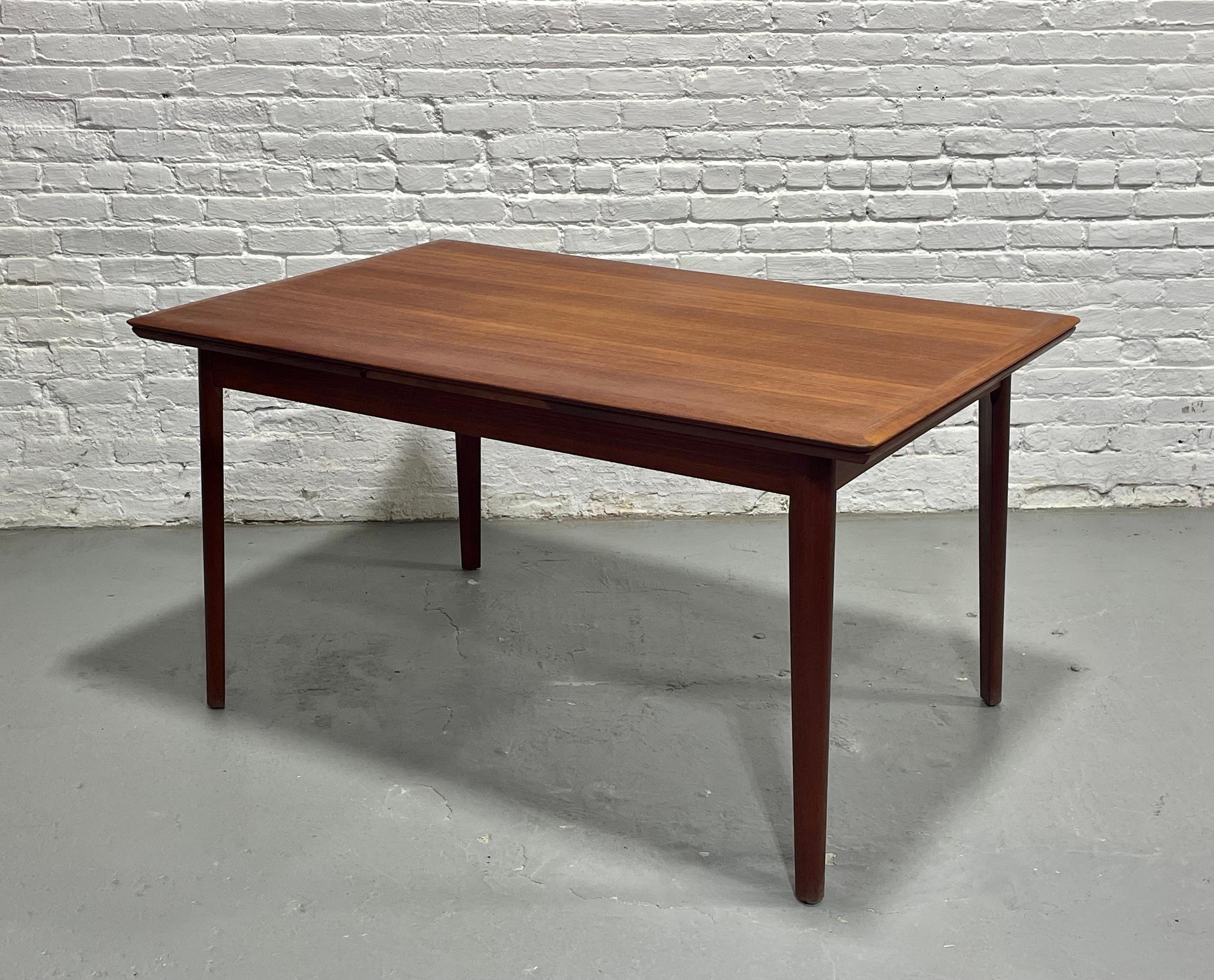 Danish Mid Century Modern TEAK DINING TABLE with two hidden leaves in a lovely streamlined size, perfect for smaller homes. The table is impeccably crafted with stunning wood grains and features two hidden leaves underneath the tabletop that easily