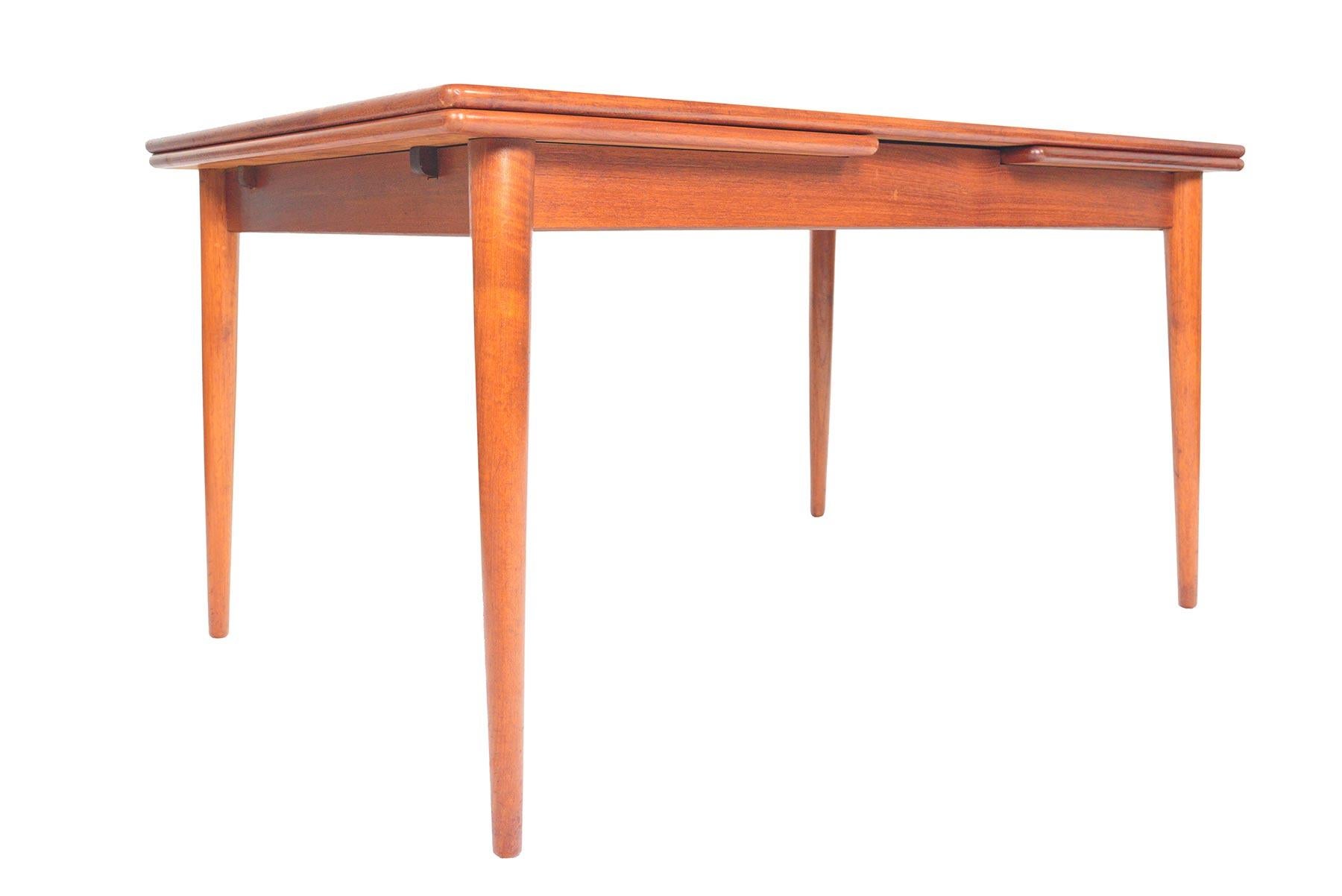 This gorgeous Danish modern teak dining table offers sleek banding and a tapered leg. Two draw leaves pull-out to almost double the size of the table for entertaining. Table extends to 96
