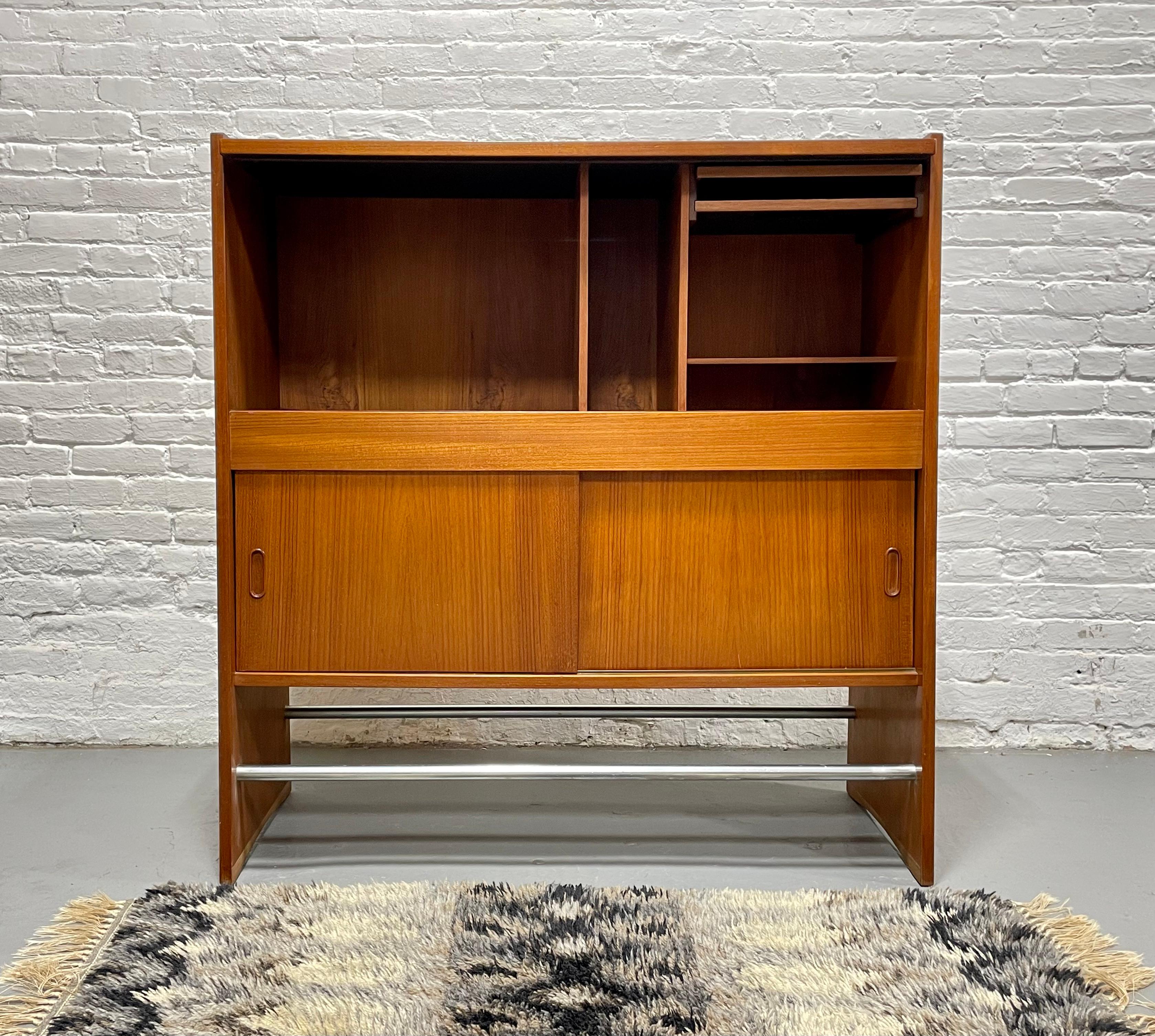 Danish Mid Century Modern Teak Dry Bar attributed to Erik Buch, c. 1960s.  One side features a finished teak side with gorgeous wood grains and a metal footrest for guests and the back offers storage for eight wine bottles, a pullout shelf for ice