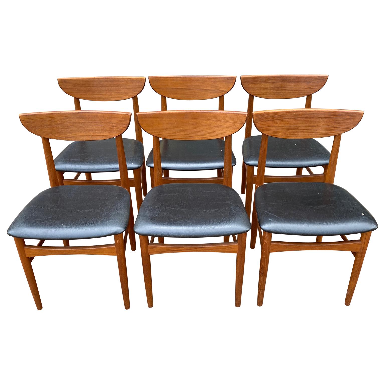 Mid-Century Modern Danish teak Dyrlund dining chairs. Complete set of eight dining chairs with black leatherette seats in very good condition. All eight chairs are without arms making them easily comfortable to fit into any dining table. The teak is