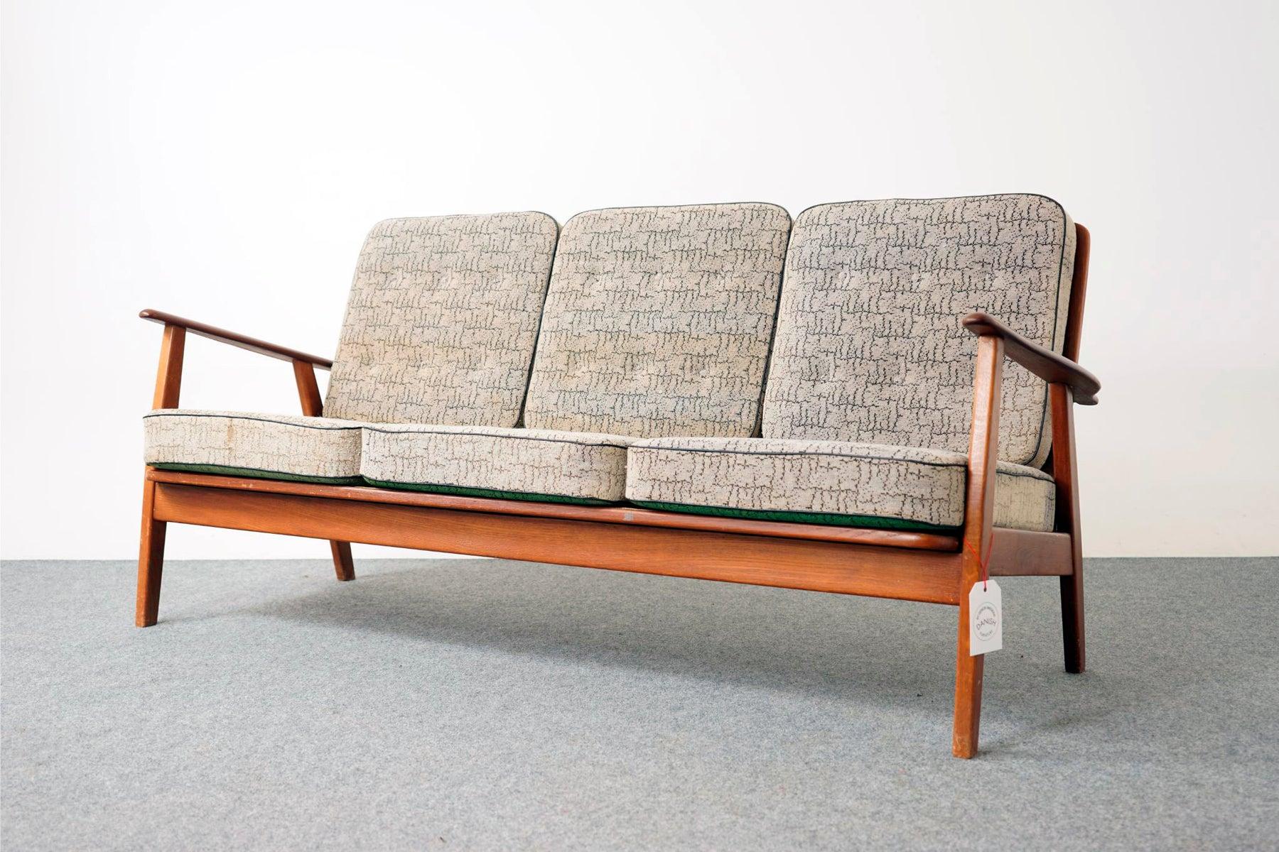 Teak and oak Mid-Century Modern sofa, circa 1950's. Three seat sofa frame is constructed of solid teak and with removable cushions on both the seat and backrest. Sofa shows beautifully sculpted teak arm rests.

Unrestored item, some marks