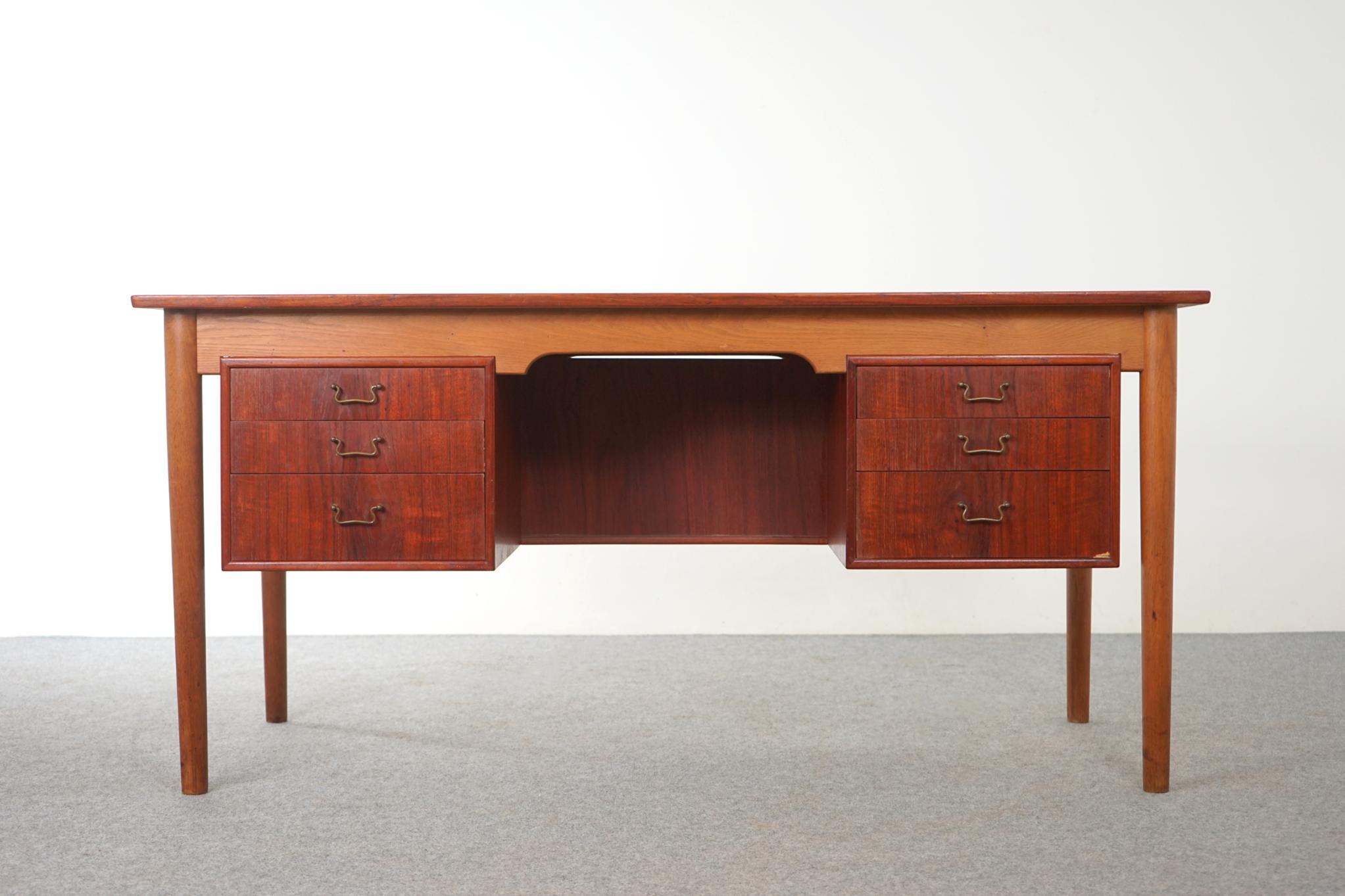 Teak & oak Danish desk, circa 1950's. Oak frame contrasts beautifully with the book matched teak veneer top. Finished on both sides, place this in the center of a room and it will look fantastic from everywhere! Dovetailed drawers have charming