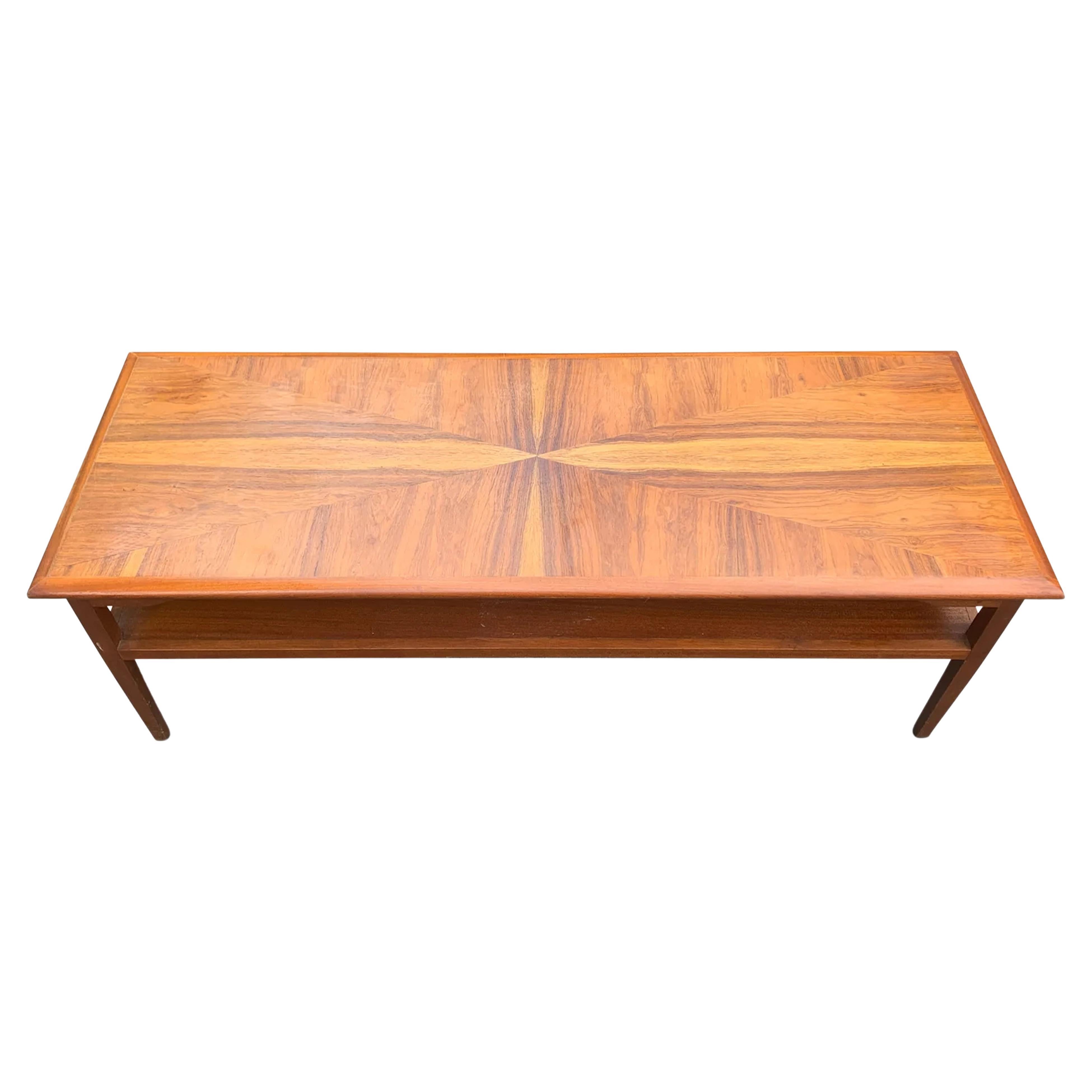 A Danish Mid Century Modern Teak Rectangular  Coffee Table With Magazine Rack Featuring A Sunburst Inlaid Table Top from the 1960's 

An unusual twist on a teak mid century coffee table, with an eye catching sunburst inlaid top.