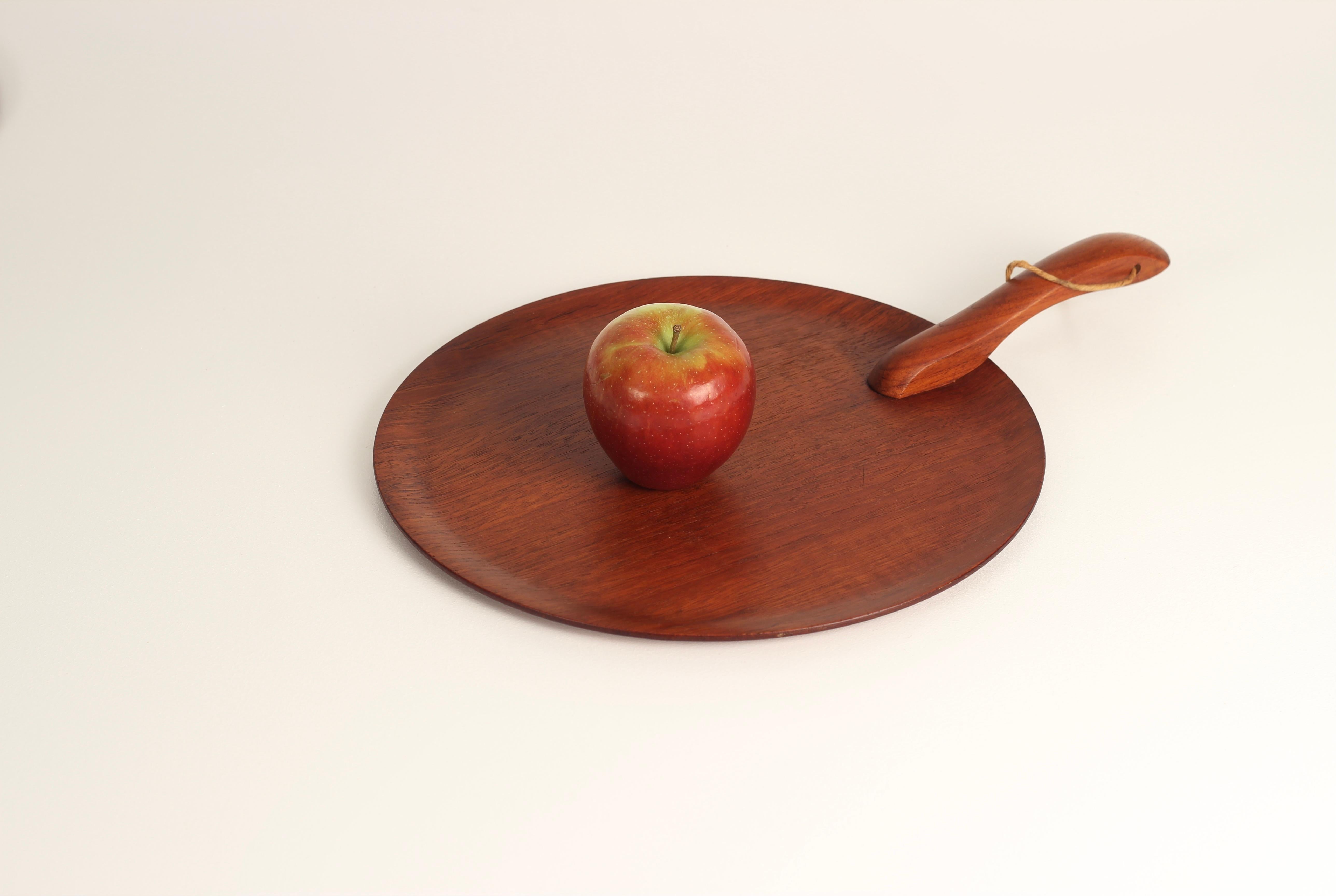 A Danish Mid-Century Modern Scandinavian design serving platter or cheese board in the style of Kay Bojesen. A sleekly designed handle with a hole for a strap to hang, glides over the top of a steam bent circular plate with profiled edges.