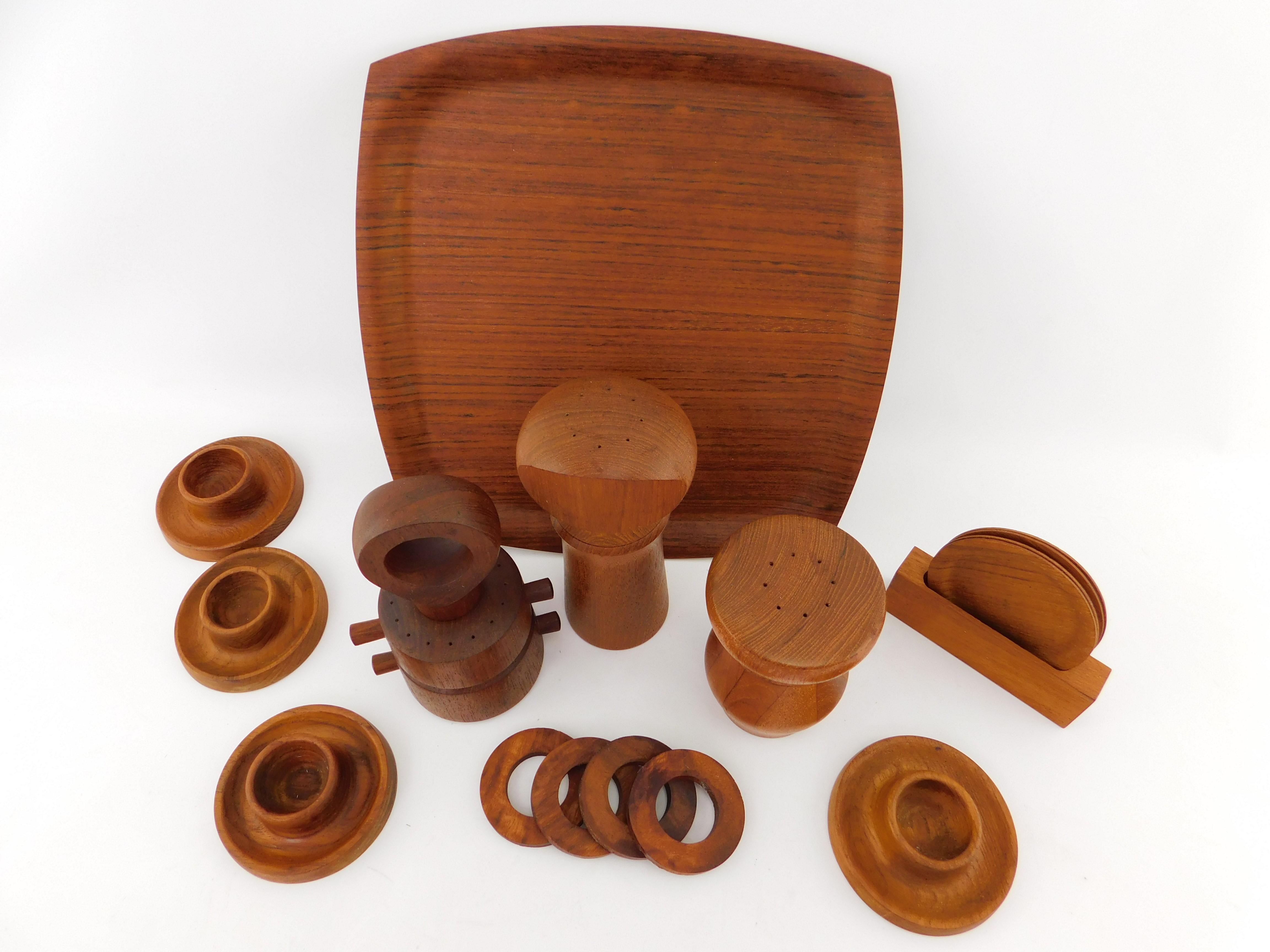 Beautiful Danish teak wood serving set featuring three pepper mills, a serving tray, four coasters in a holder, four egg holders and four napkin holders. Dimensions are; Serving Tray  cutting board 12.5
