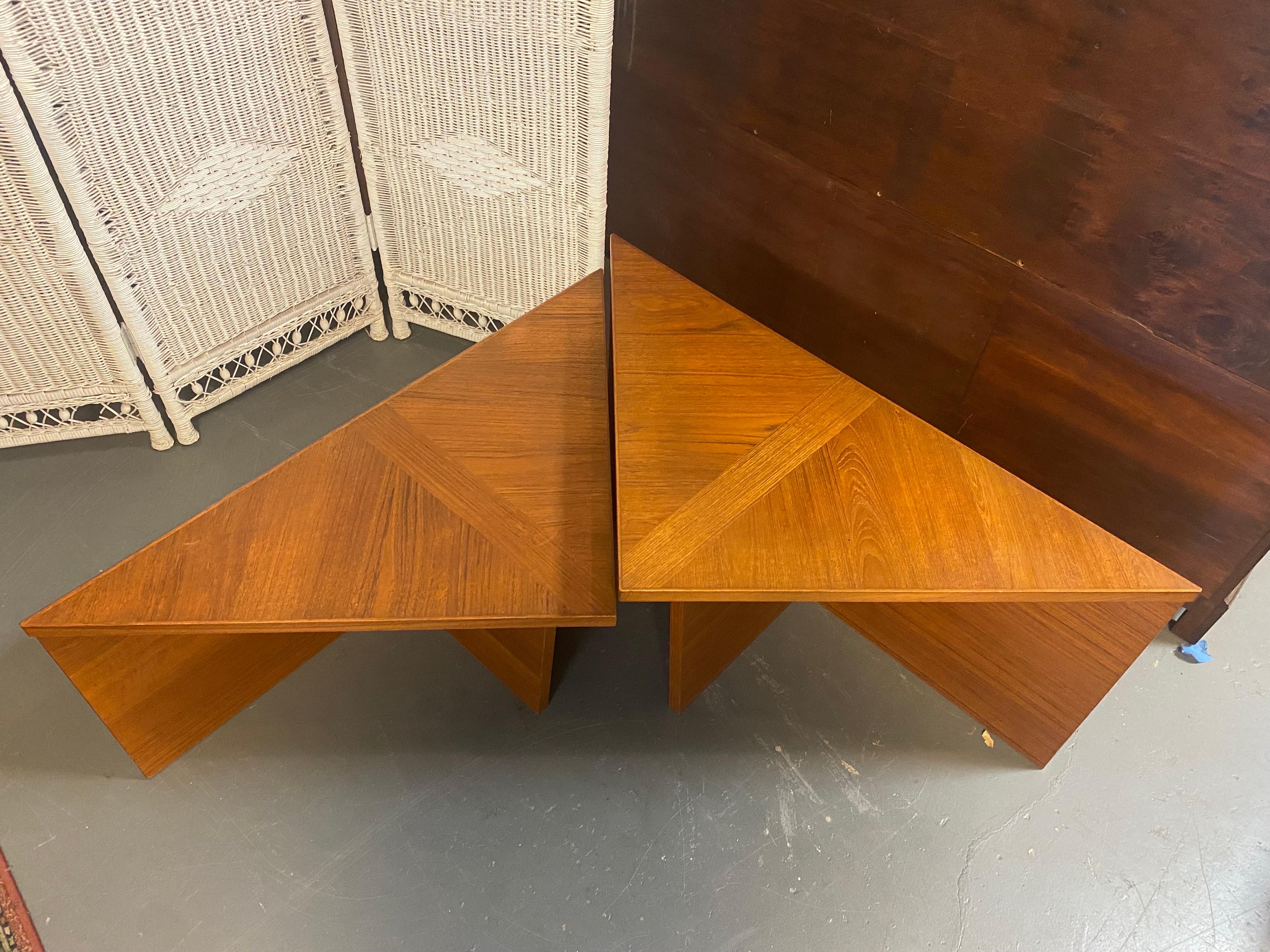 Beautiful Danish Mid-Century Modern pair of teak triangle side tables with the same surface dimensions, but different heights. The tables stand out due to their simple and straightforward design and shape. These tables are versatile and can be