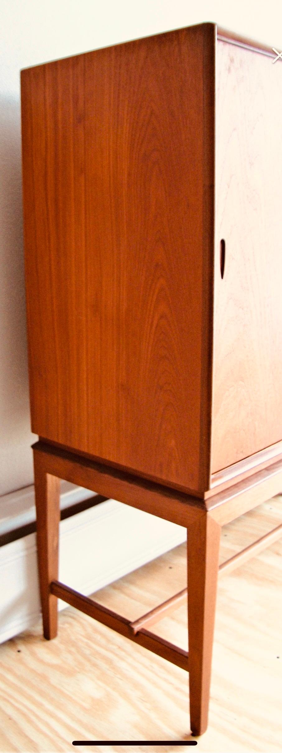 Danish modern teak sideboard with sliding doors. Classic clean lines and is raised on a 18 inch base with six square tapered teak legs on stretchers. The case is faced with a bullnose edge and the doors have easy to use door pulls. The center opens