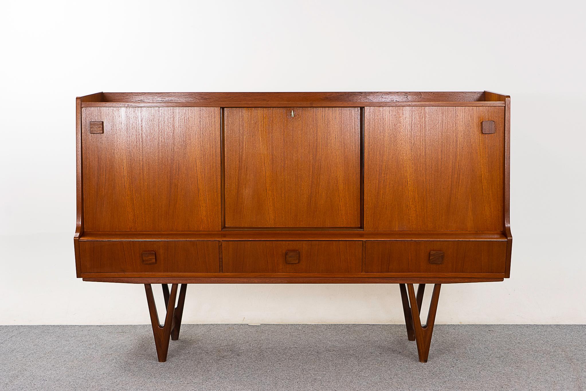 Teak mid-century sideboard, circa 1960's. This piece has stature! Beautiful case sits upon stunning, sculptural angled legs. Mirrored bar with a cut out for tall bottles, extraordinary rosewood interior wood grain patterning and drink mixing