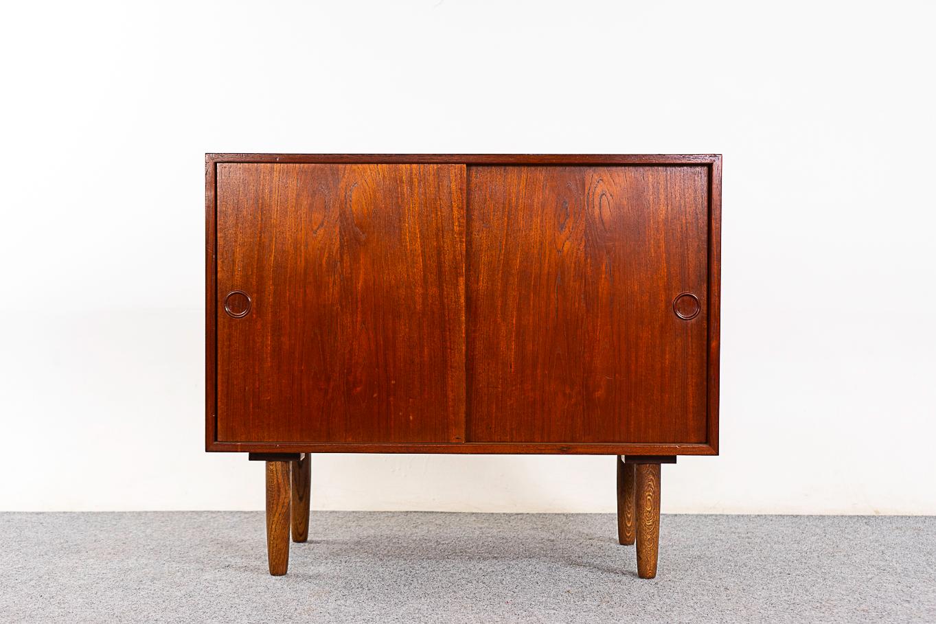 Teak Danish cabinet, circa 1960's. Clean, simple lined design with lovely book-matched veneer. Drawer and shelf are height adjustable. Contrasting solid oak legs.  

Unrestored item with option to purchase in restored condition for an additional