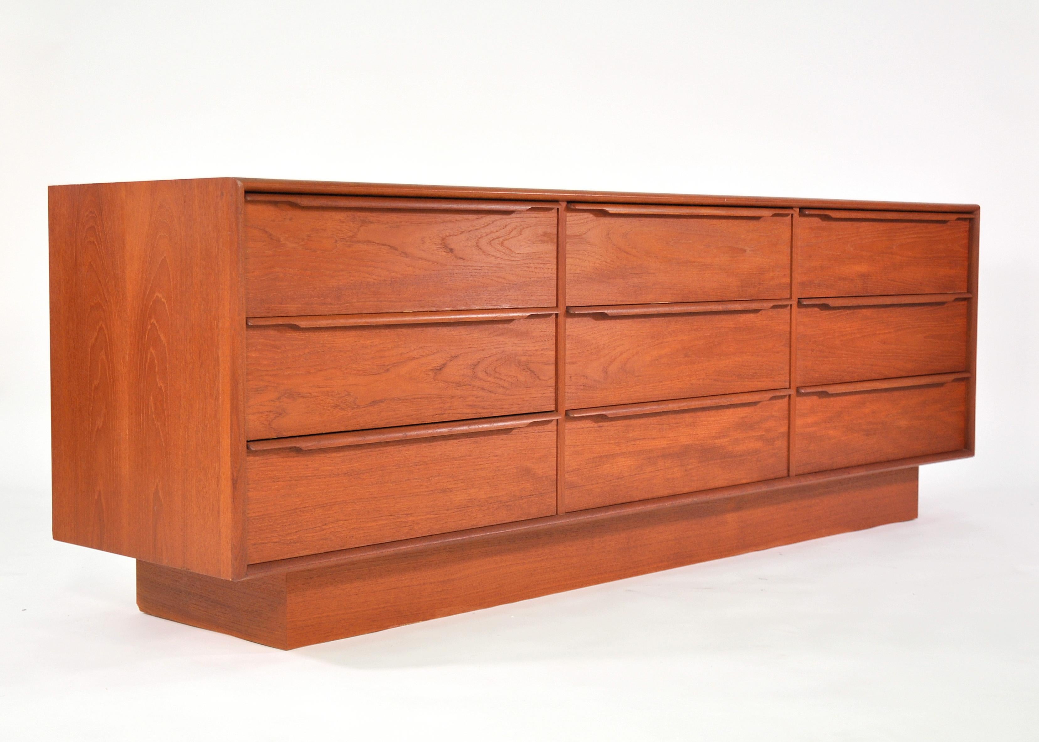 Both gorgeous and functional, this Scandinavian Modern credenza dates from the 1970s. With a total of 9 drawers, it provides a ton of storage space. The vintage dresser features beautifully sculpted teak handles and a plinth base. The grain and