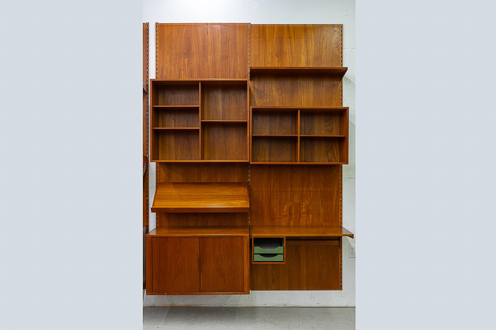Teak Danish wall system by Kai Kristiansen, circa 1960's. Fantastic double bank wall system with stunning book-matched veneer and dovetail construction. Modular components mount with 3 rails, back panel use is optional. Includes: tambour door