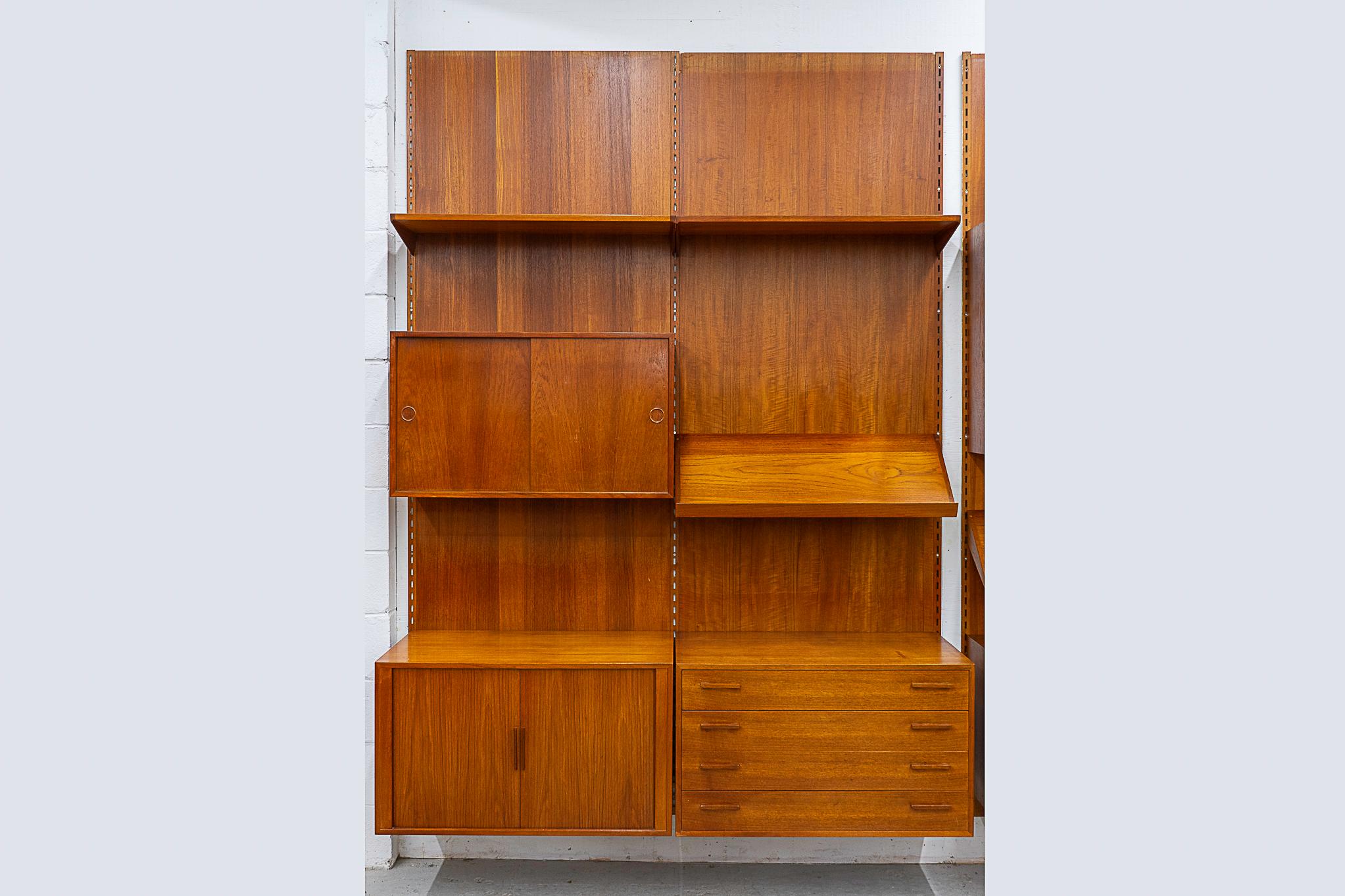 Teak Danish wall system by Kai Kristiansen, circa 1960's. Fantastic double bank wall system with stunning book-matched veneer and dovetail construction. Modular components mount with 3 rails, back panel use is optional. Includes: sliding door