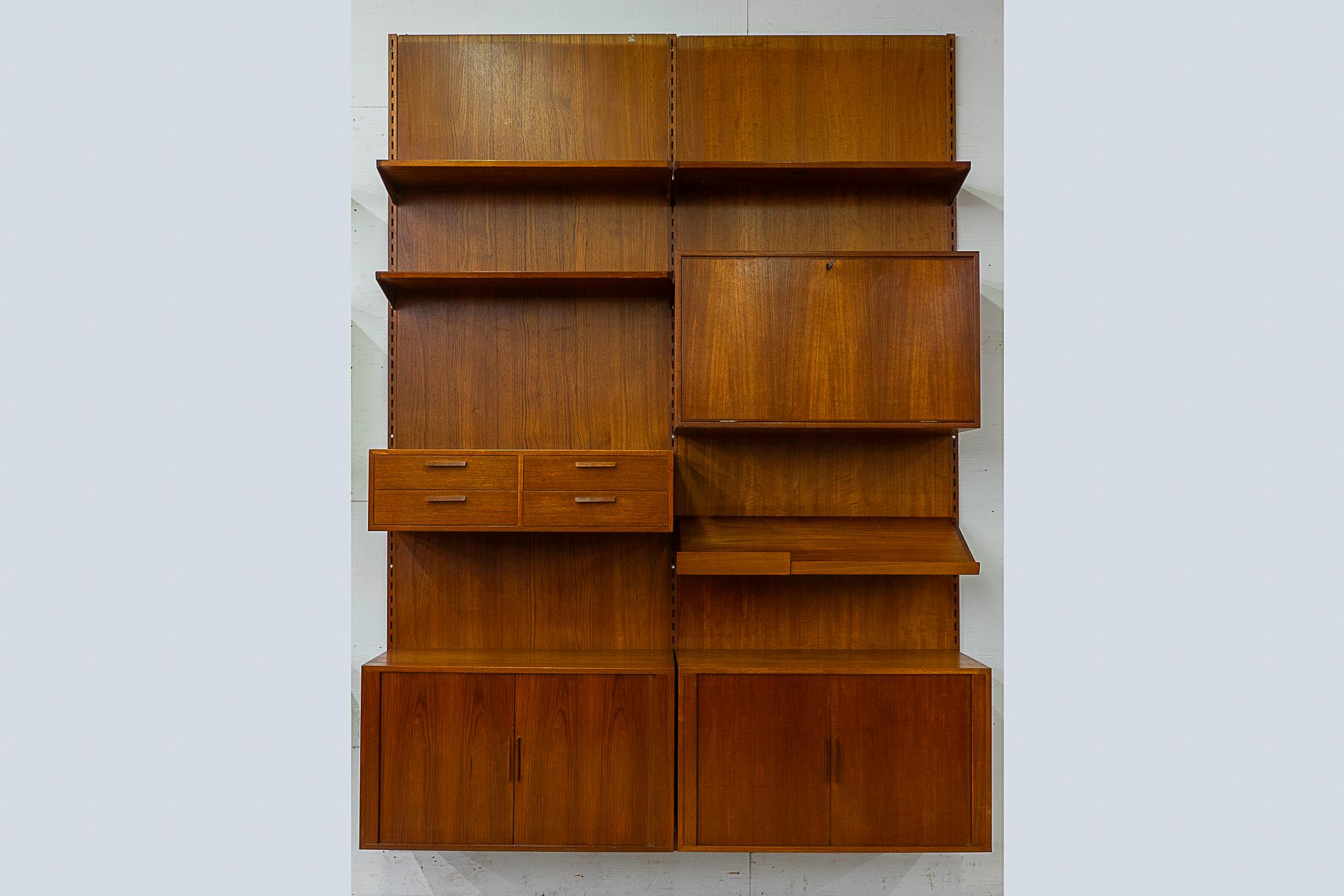 Teak Danish wall system by Kai Kristiansen, circa 1960's. Fantastic double bank wall system with stunning book-matched veneer and dovetail construction. Modular components mount with 3 rails, back panel use is optional. Includes: 2 tambour door