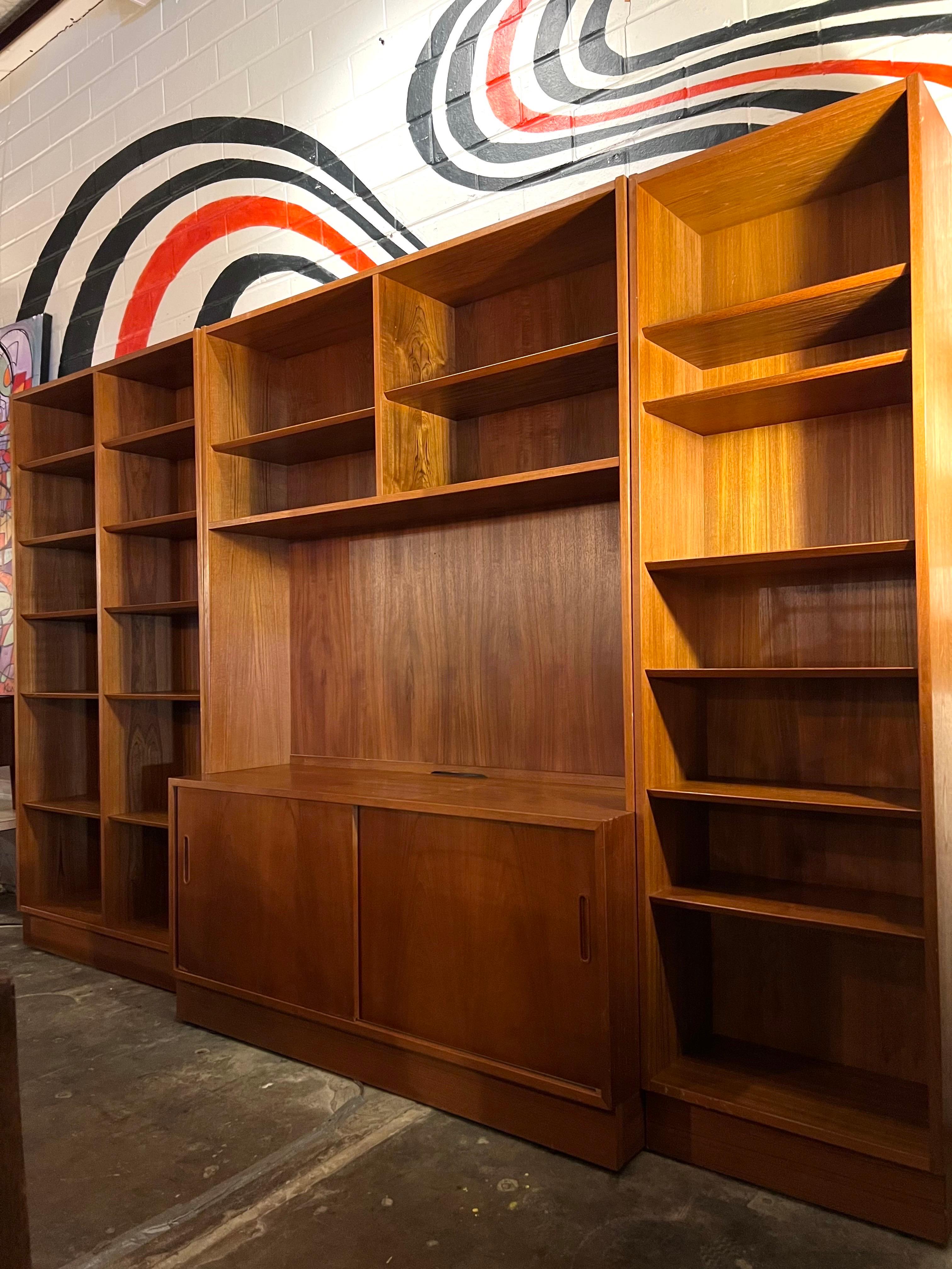 Beautiful Danish Mid-Century Modern teak wall unit by Carlo Jensen for Hundevad & Co., Denmark, circa 1960s. The wall unit consists of three separate sections featuring beautiful graining. The middle piece consist of sliding doors with inset pulls